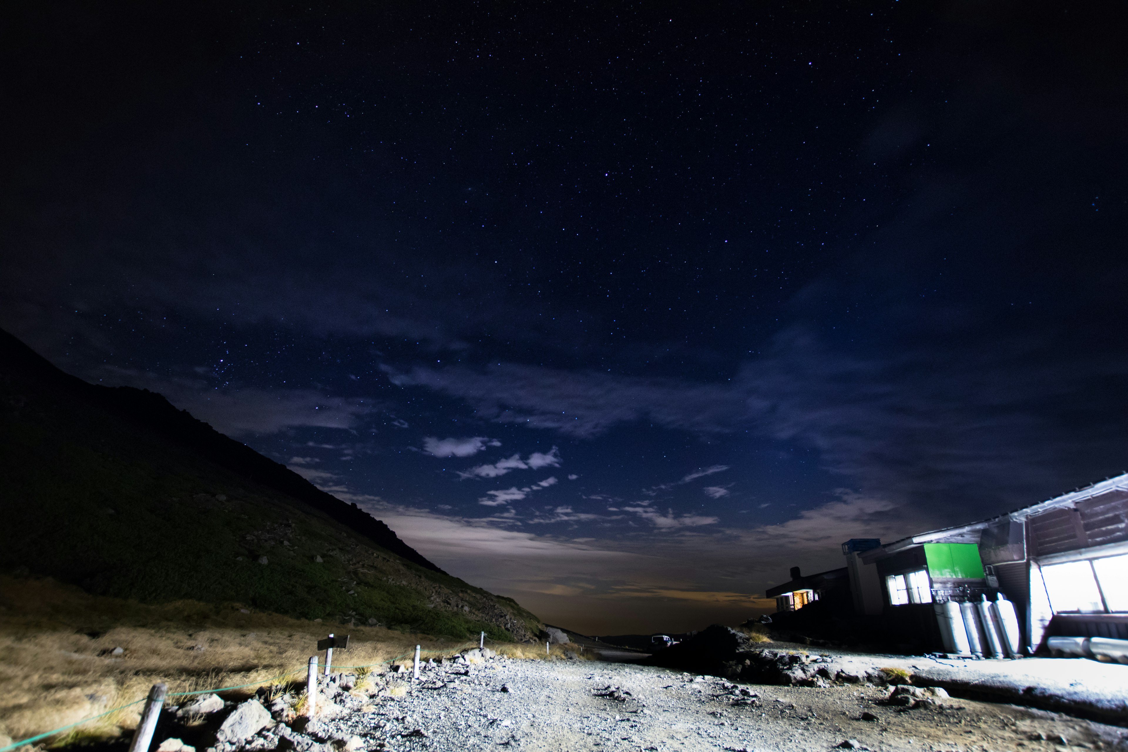 Vista panoramica di un sentiero di montagna sotto un cielo stellato con nuvole