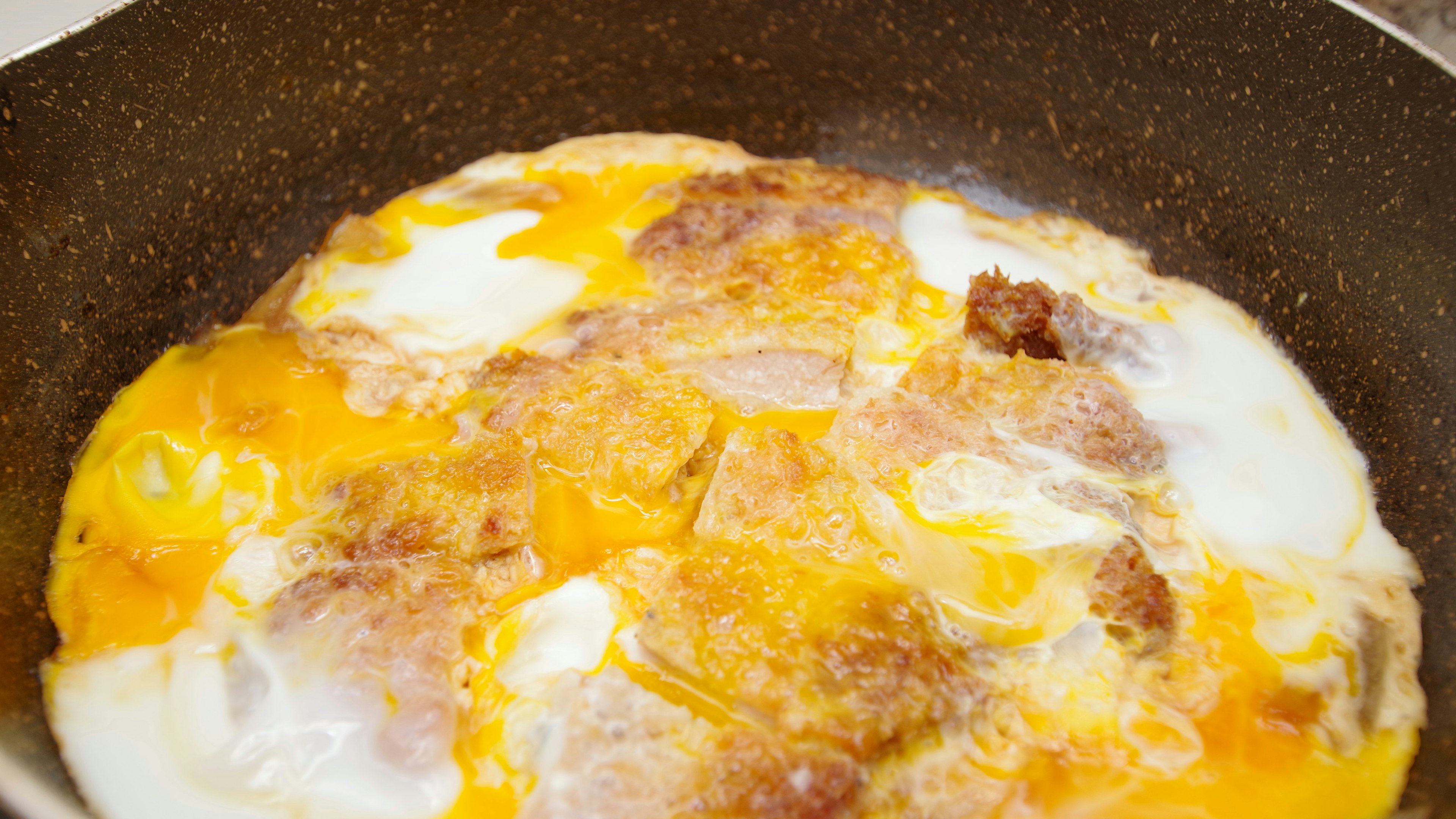 Tortilla con huevos y carne cocinándose en una sartén