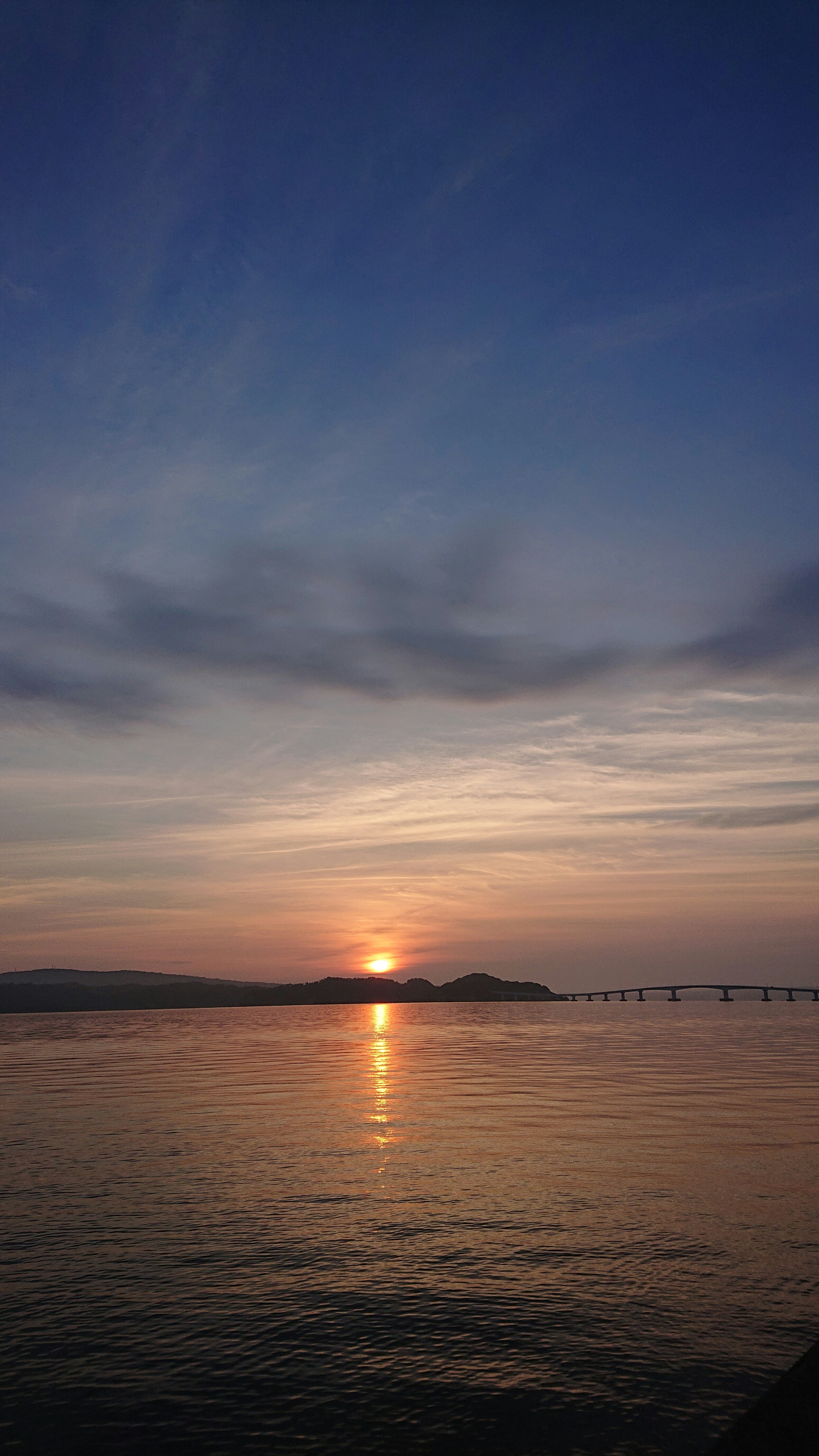 Sunset over calm waters with soft clouds in the sky