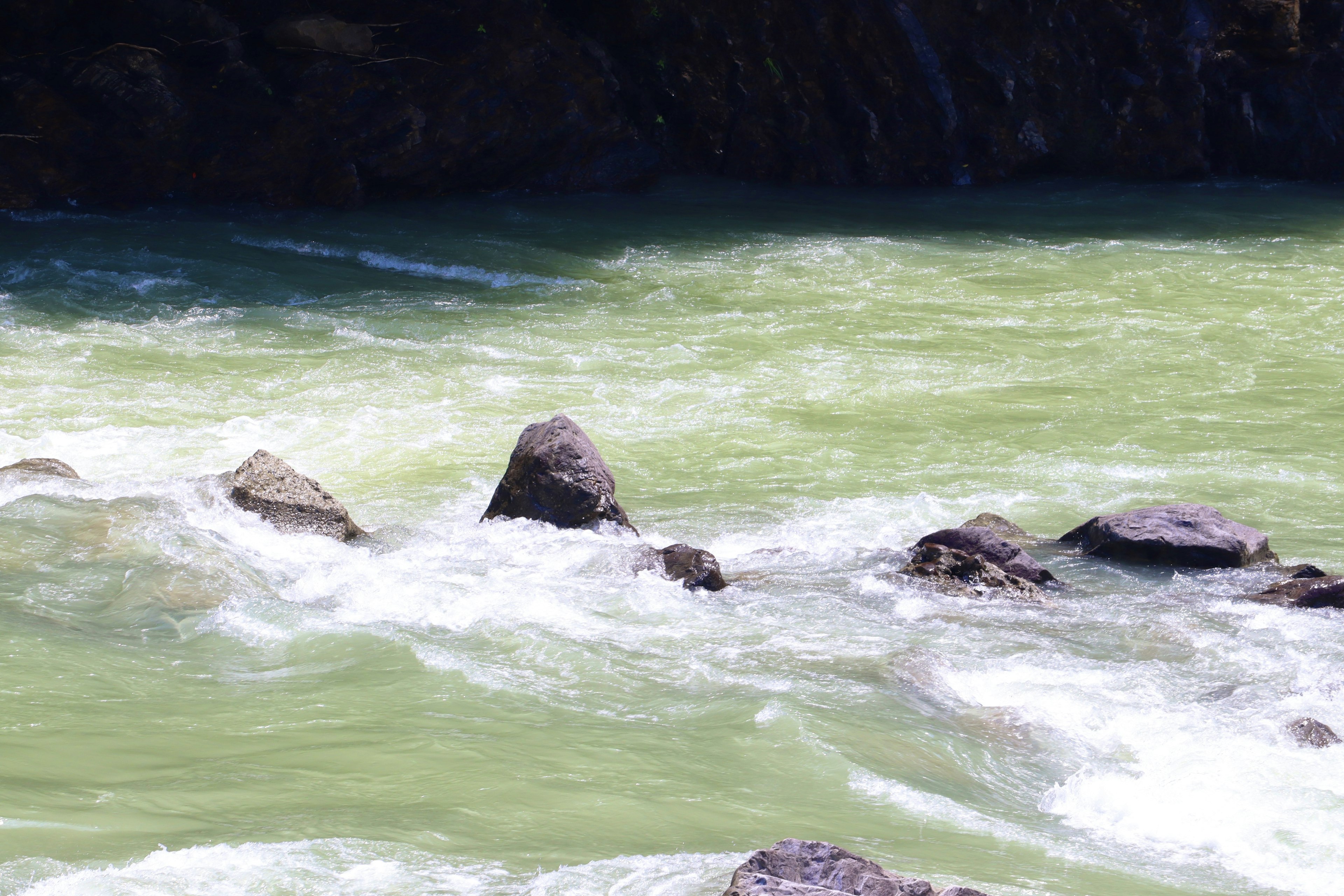 Pemandangan sungai dengan air hijau dan batu yang terlihat