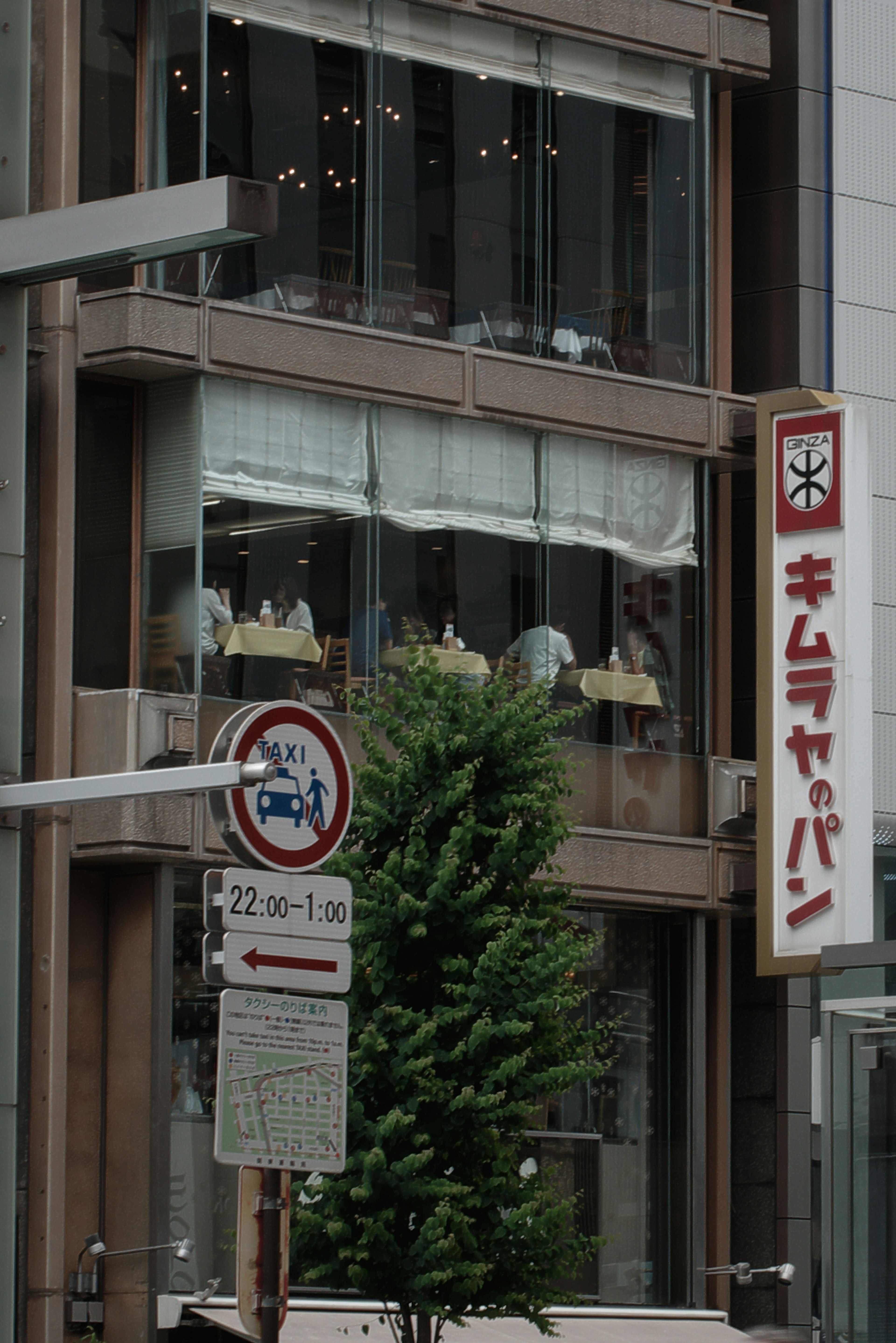 Urban scene showing building exterior and people visible through windows