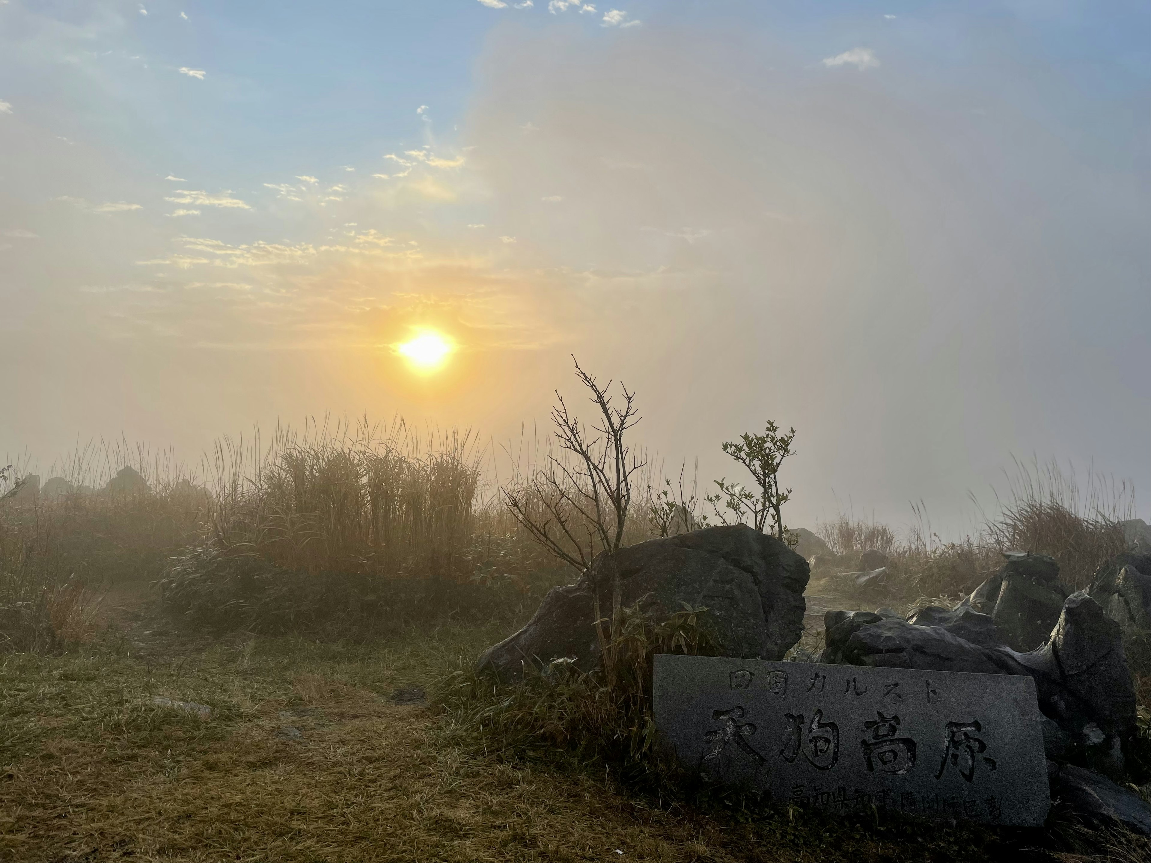 Lever de soleil dans le brouillard avec des rochers au premier plan