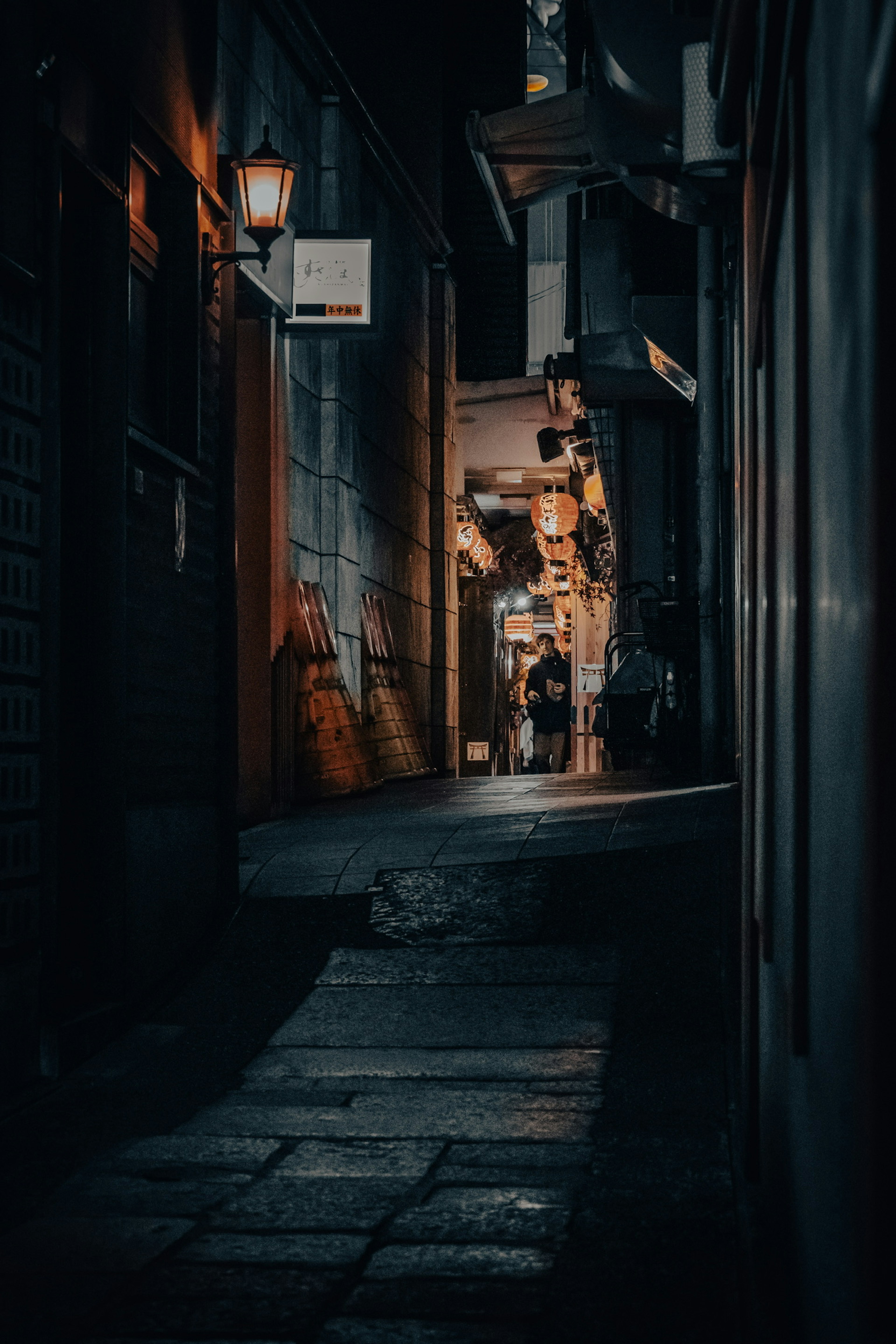 Callejón estrecho con farolas y siluetas de personas