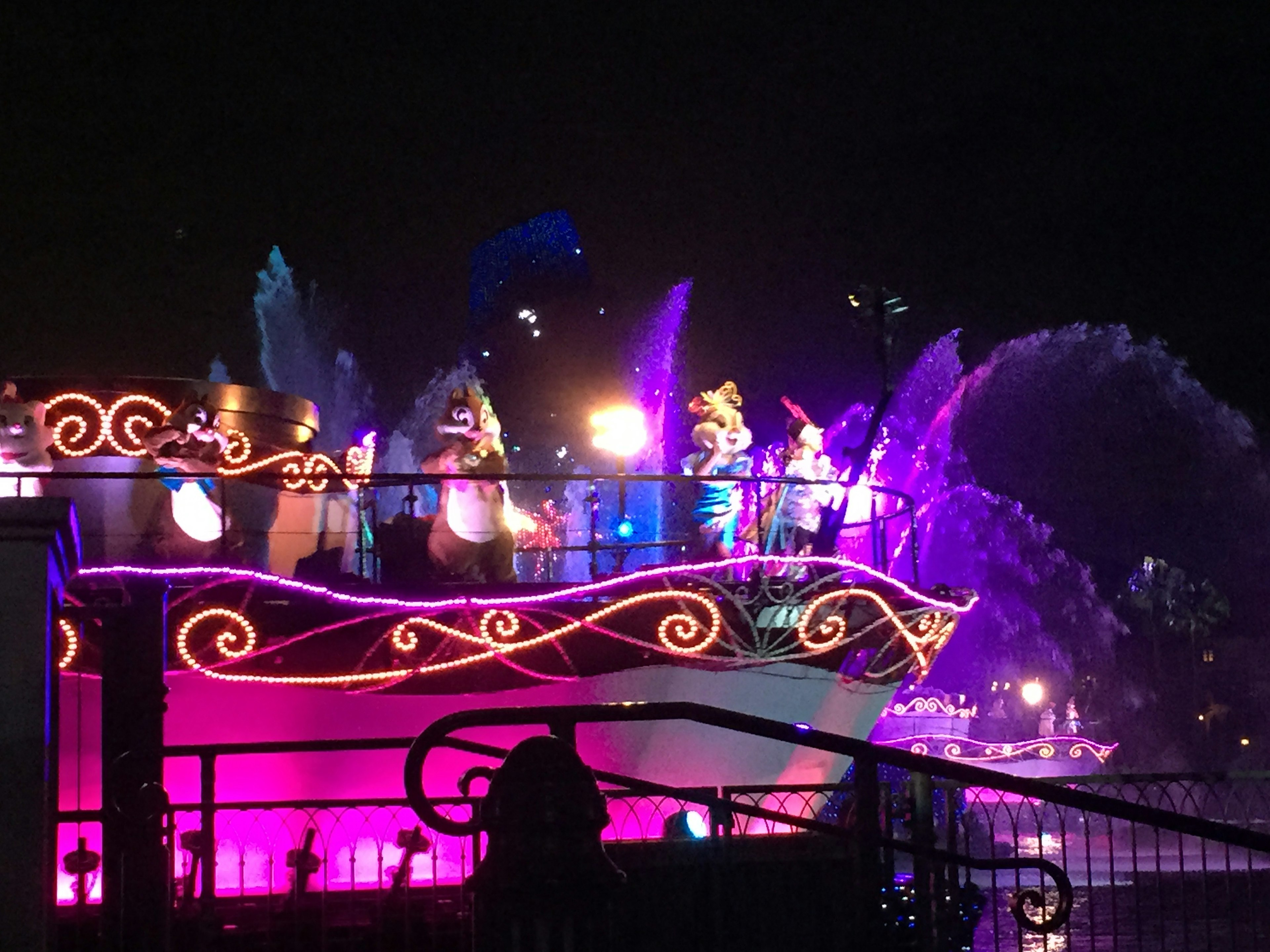 Bateau illuminé coloré avec des personnages lors d'une parade nocturne