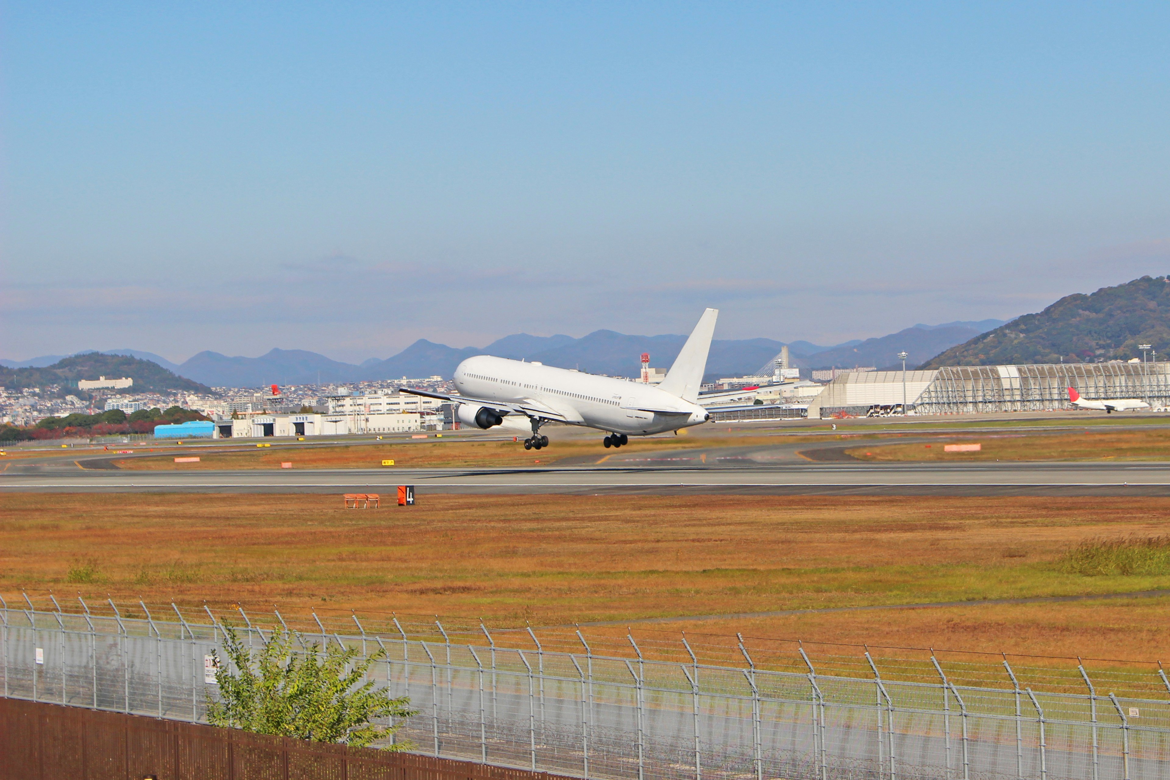 Ein weißes Flugzeug, das von einem Flughafen abhebt mit der umliegenden Landschaft