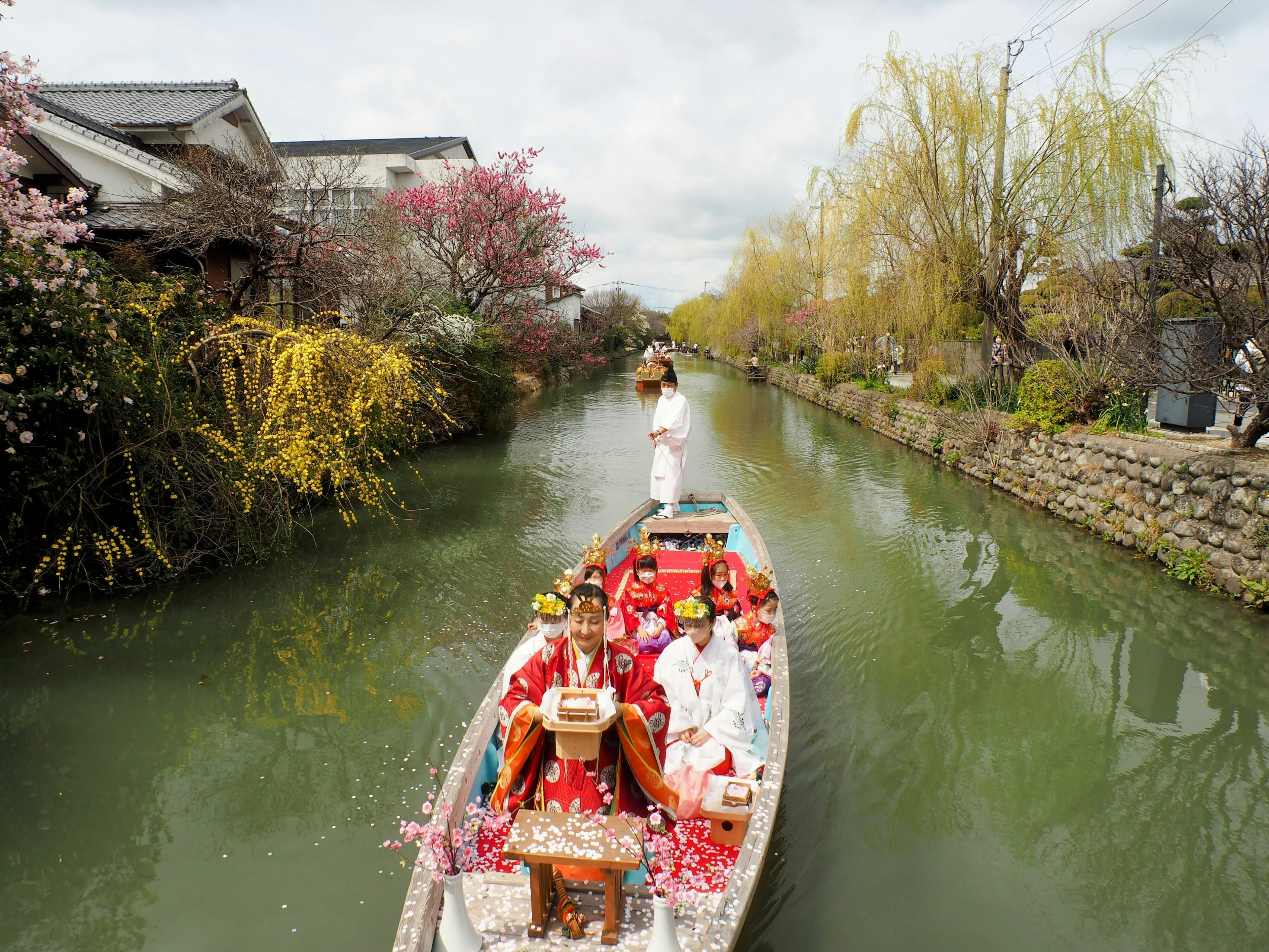 Barco japonés tradicional con personas en kimono en un canal pintoresco