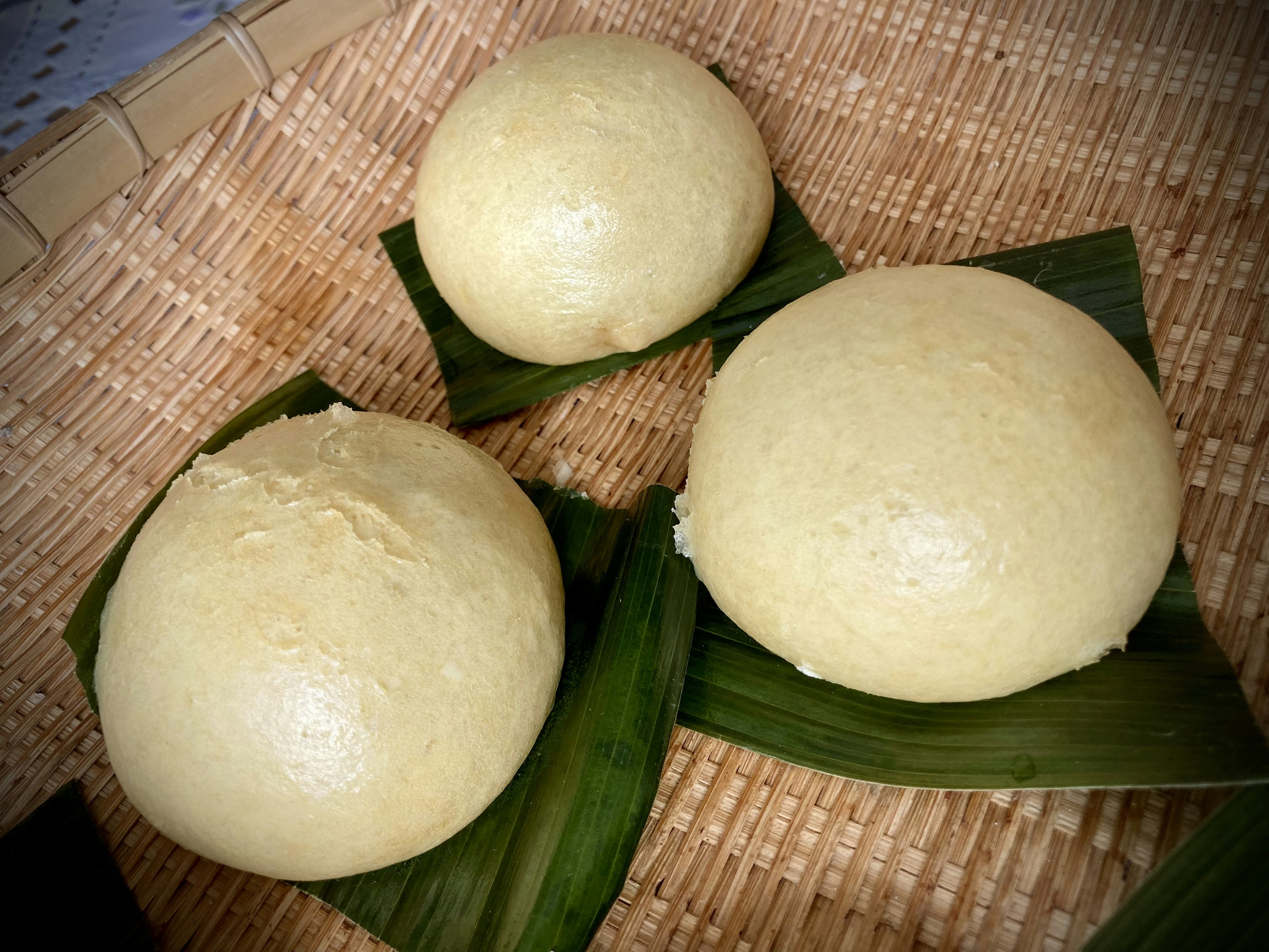 Three steamed buns placed on banana leaves