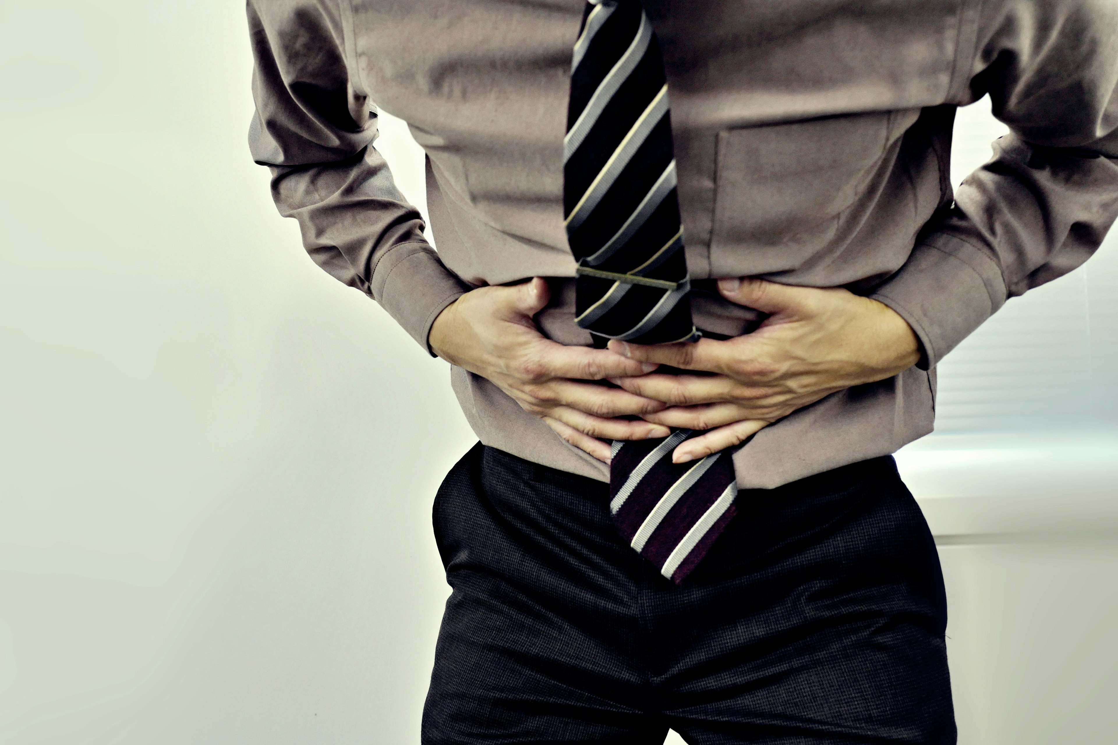 Man in shirt and tie holding his stomach