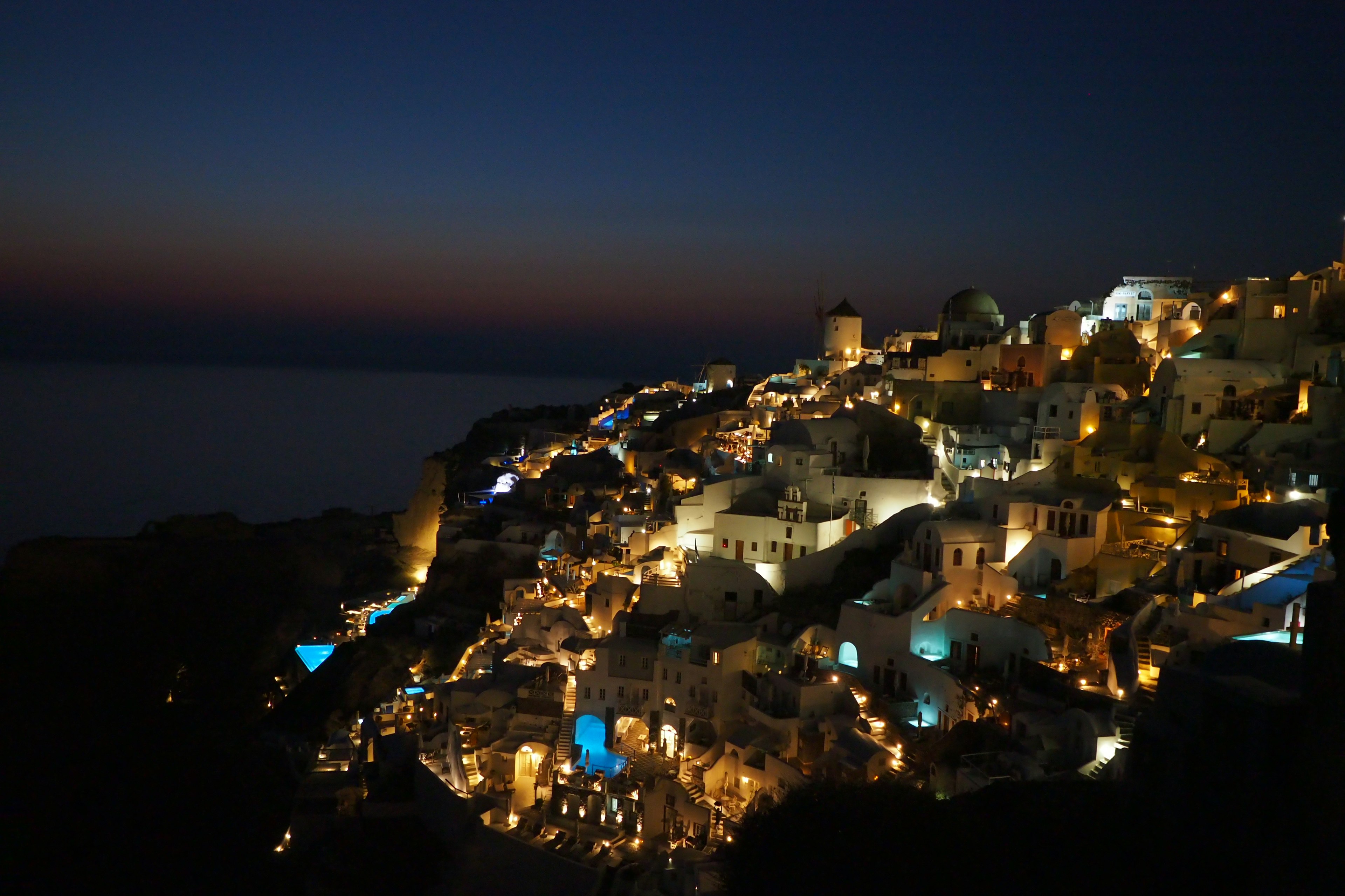 Vista escénica de un pueblo costero de noche edificios iluminados en una colina