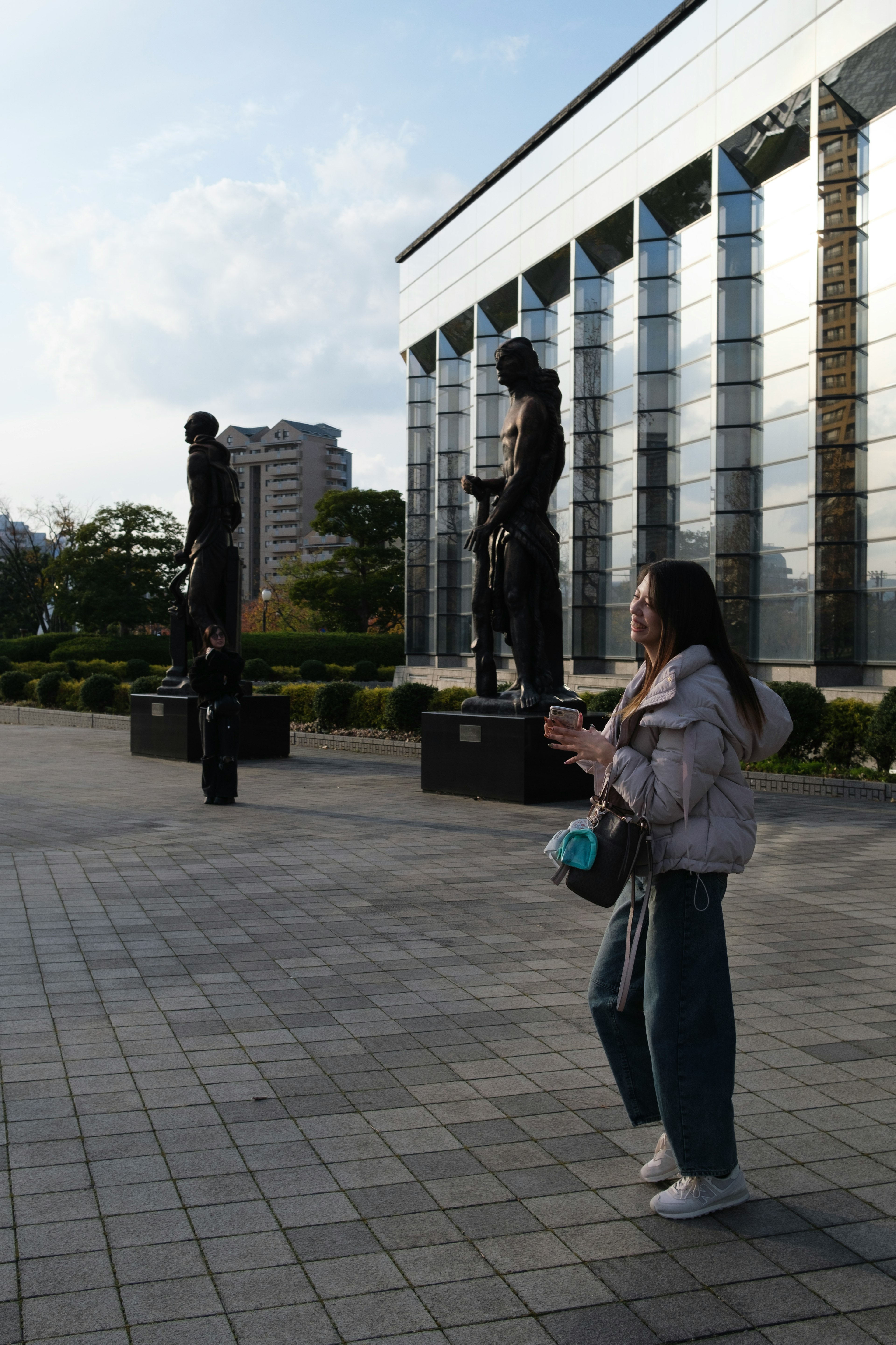 外で立つ2つの彫像の前に立っている女性の写真