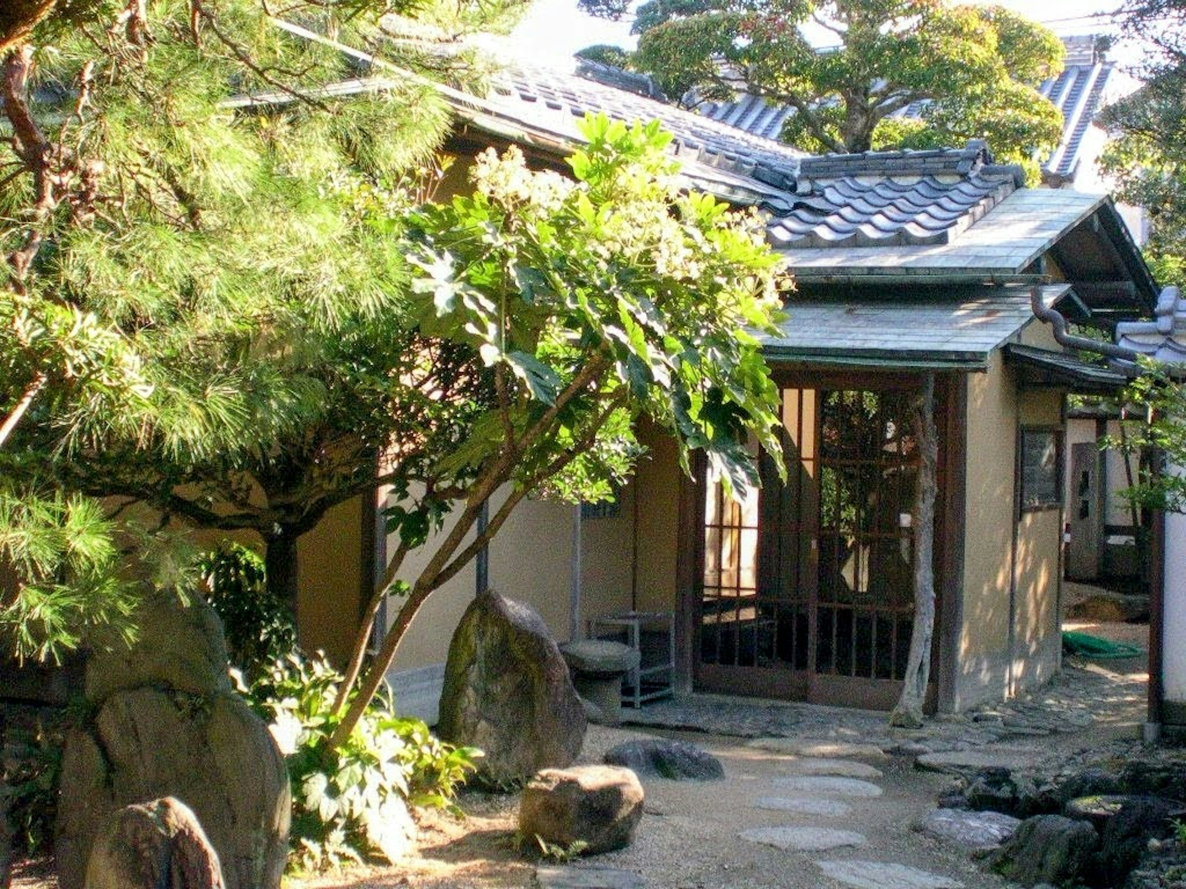 Traditionelles japanisches Haus mit Garten, der üppige Pflanzen und Steinelemente zeigt