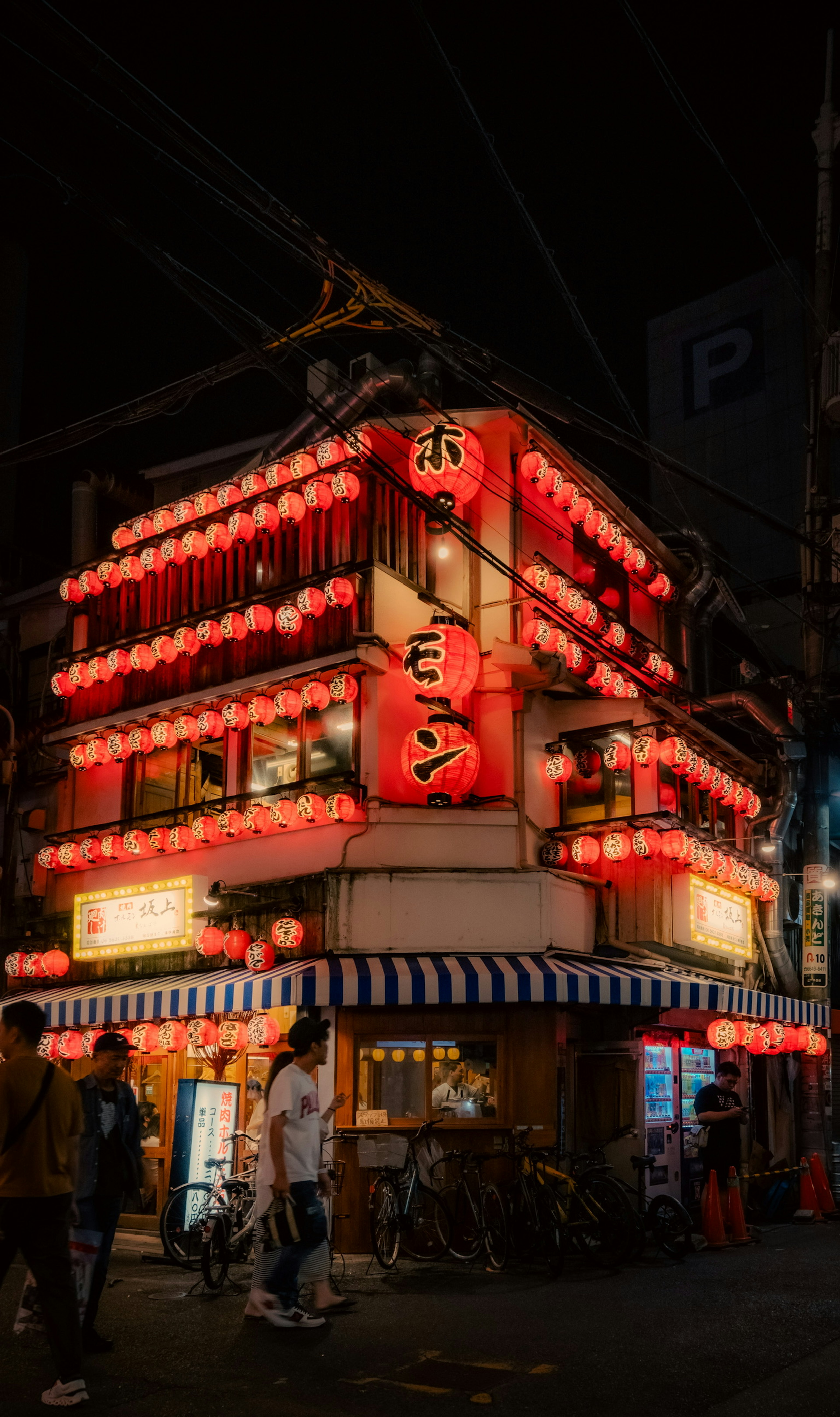 Bâtiment d'izakaya japonais décoré de lanternes rouges dans une scène de rue nocturne