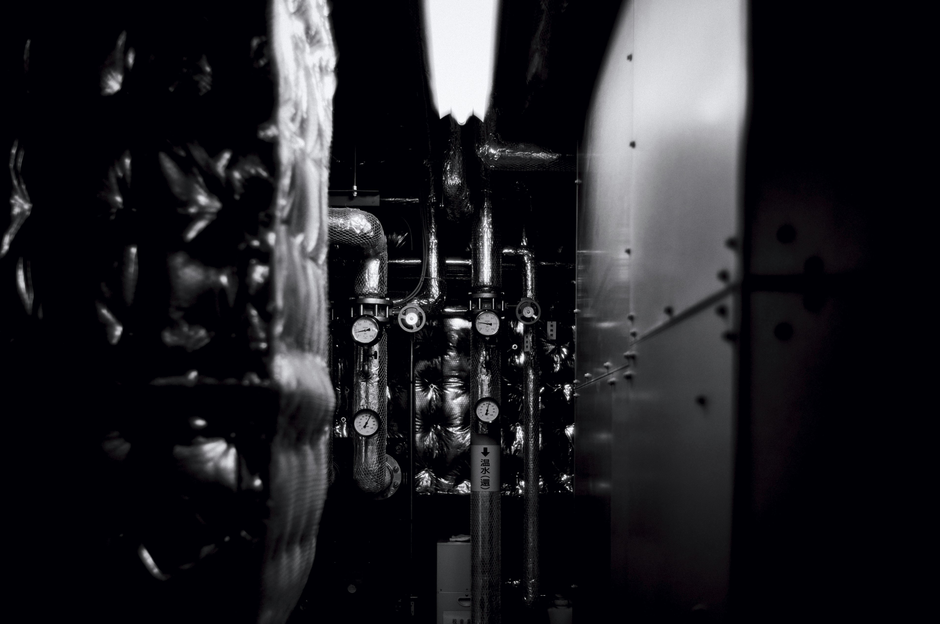 Monochrome image showing internal machinery with pipes and valves