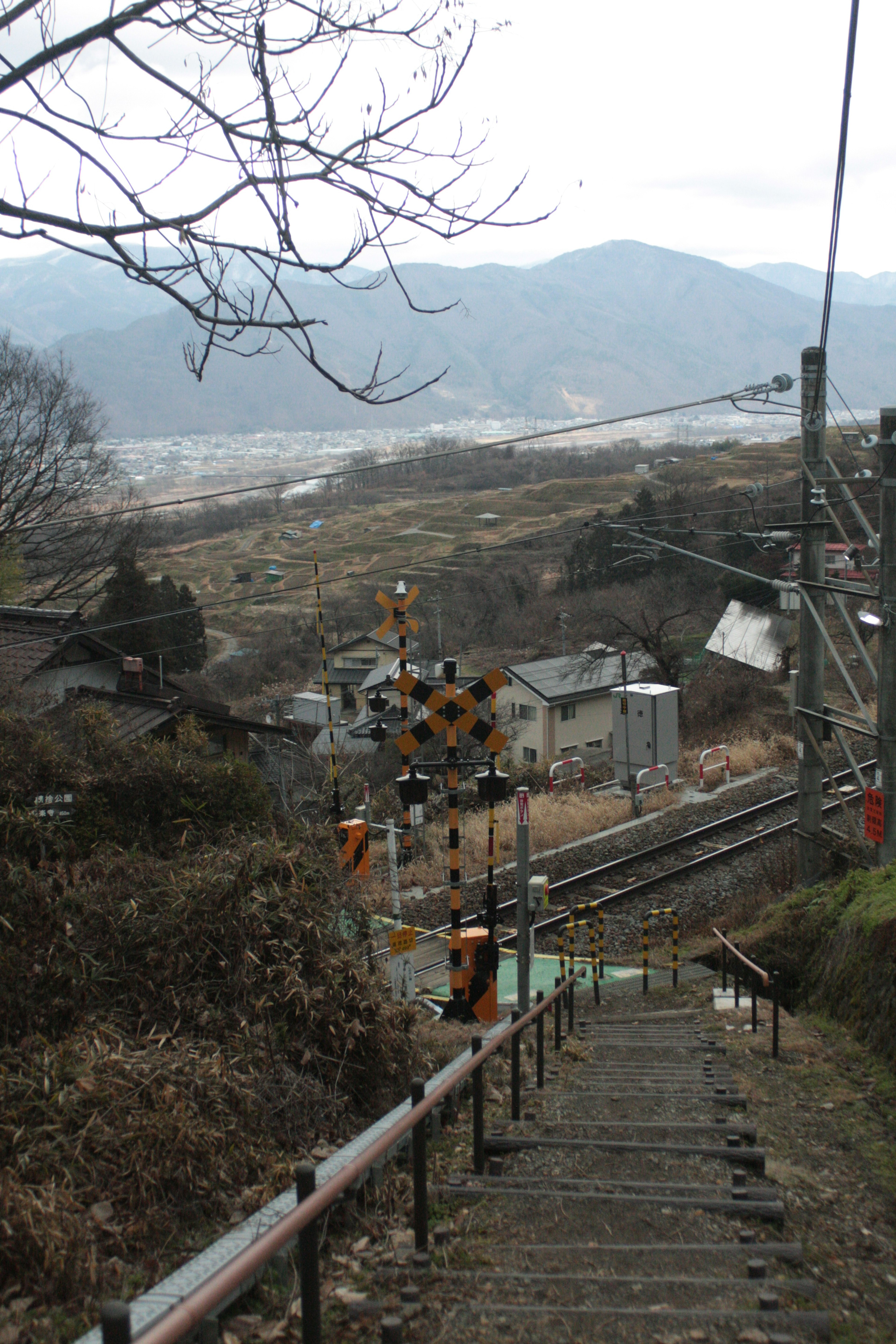 山間の鉄道と踏切が見える階段の風景