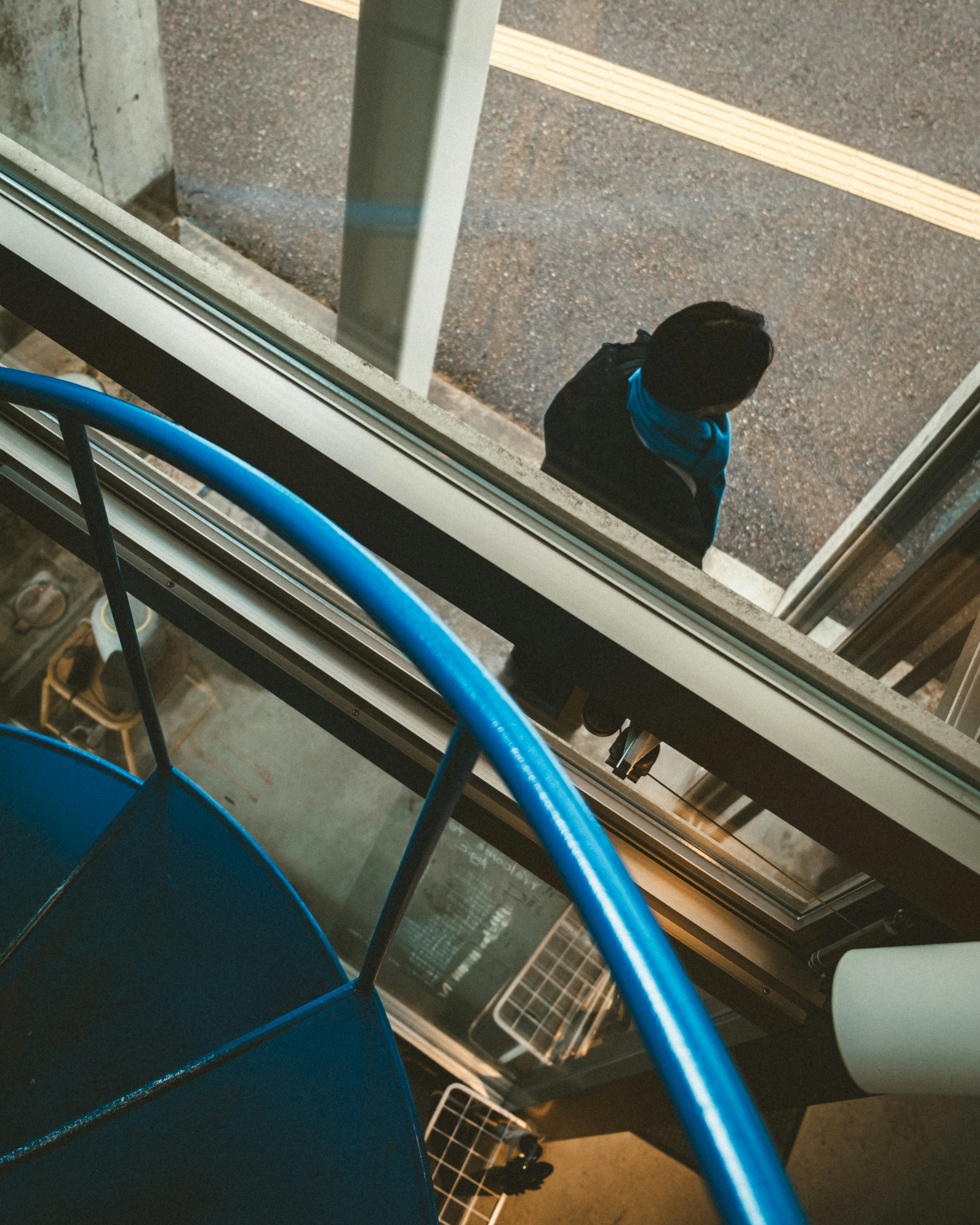 Top view of a person near a blue spiral staircase and glass window