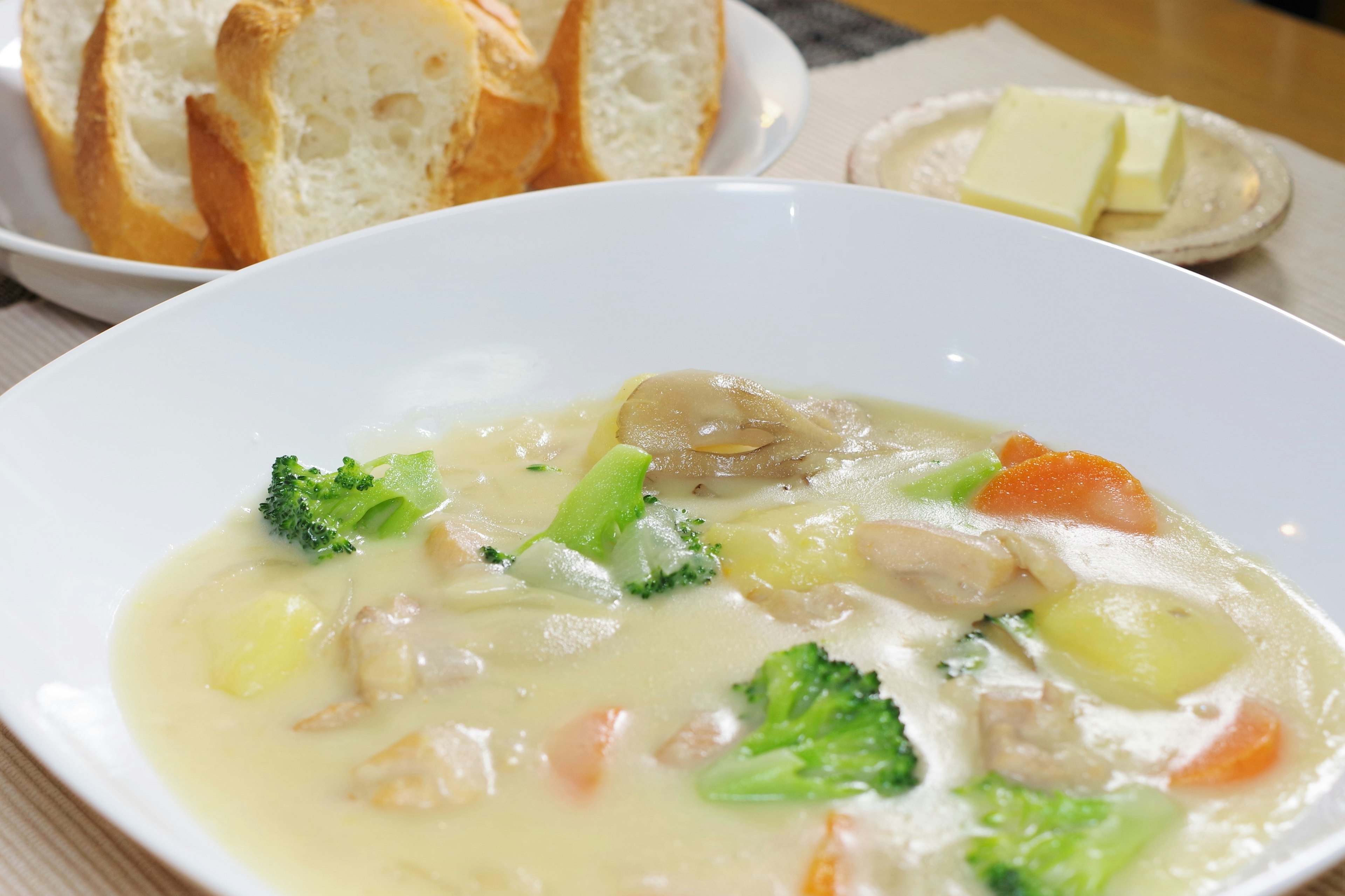 Cremige Suppe mit Gemüse und Hühnchen serviert mit Butterbrot