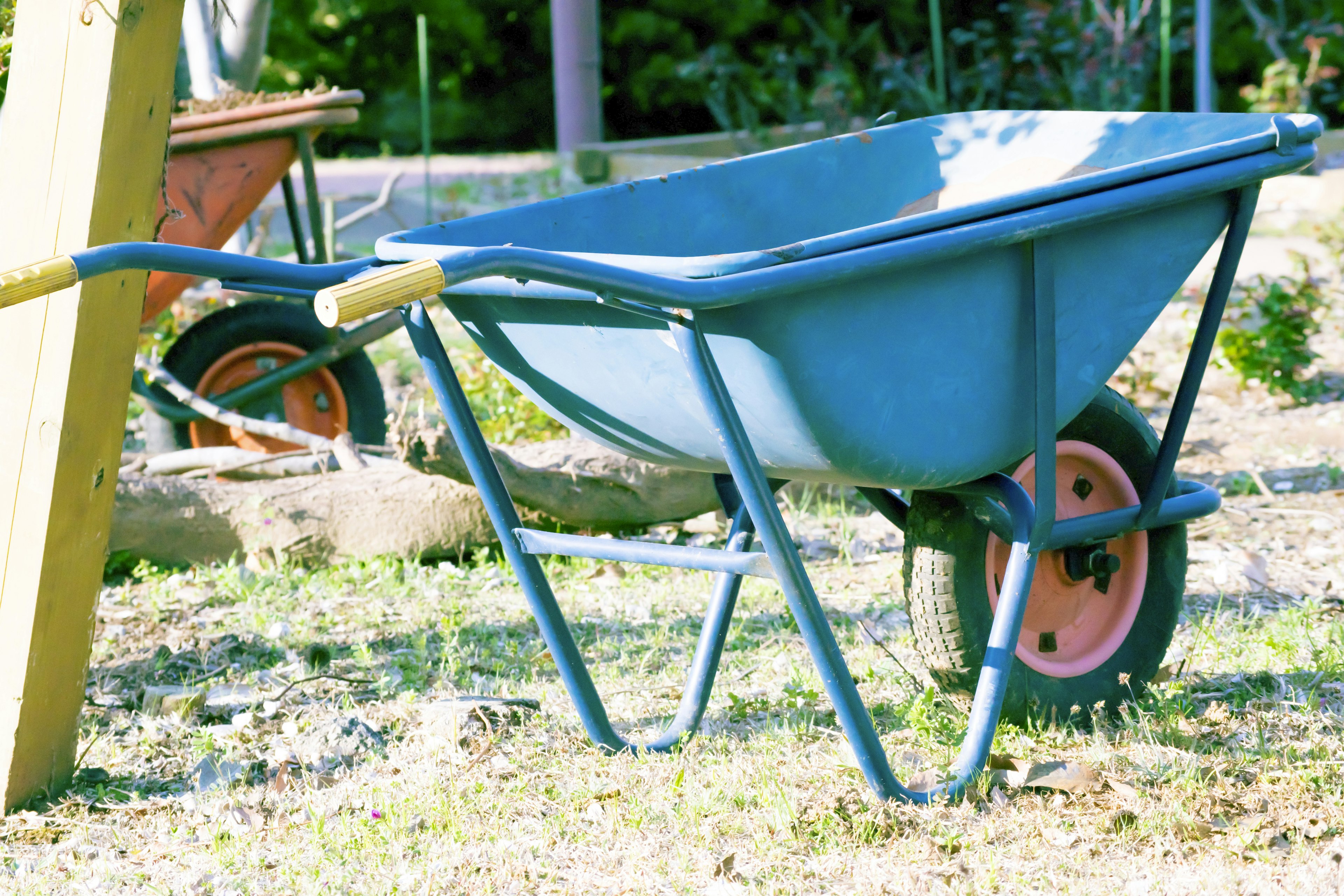 A blue wheelbarrow resting on the ground