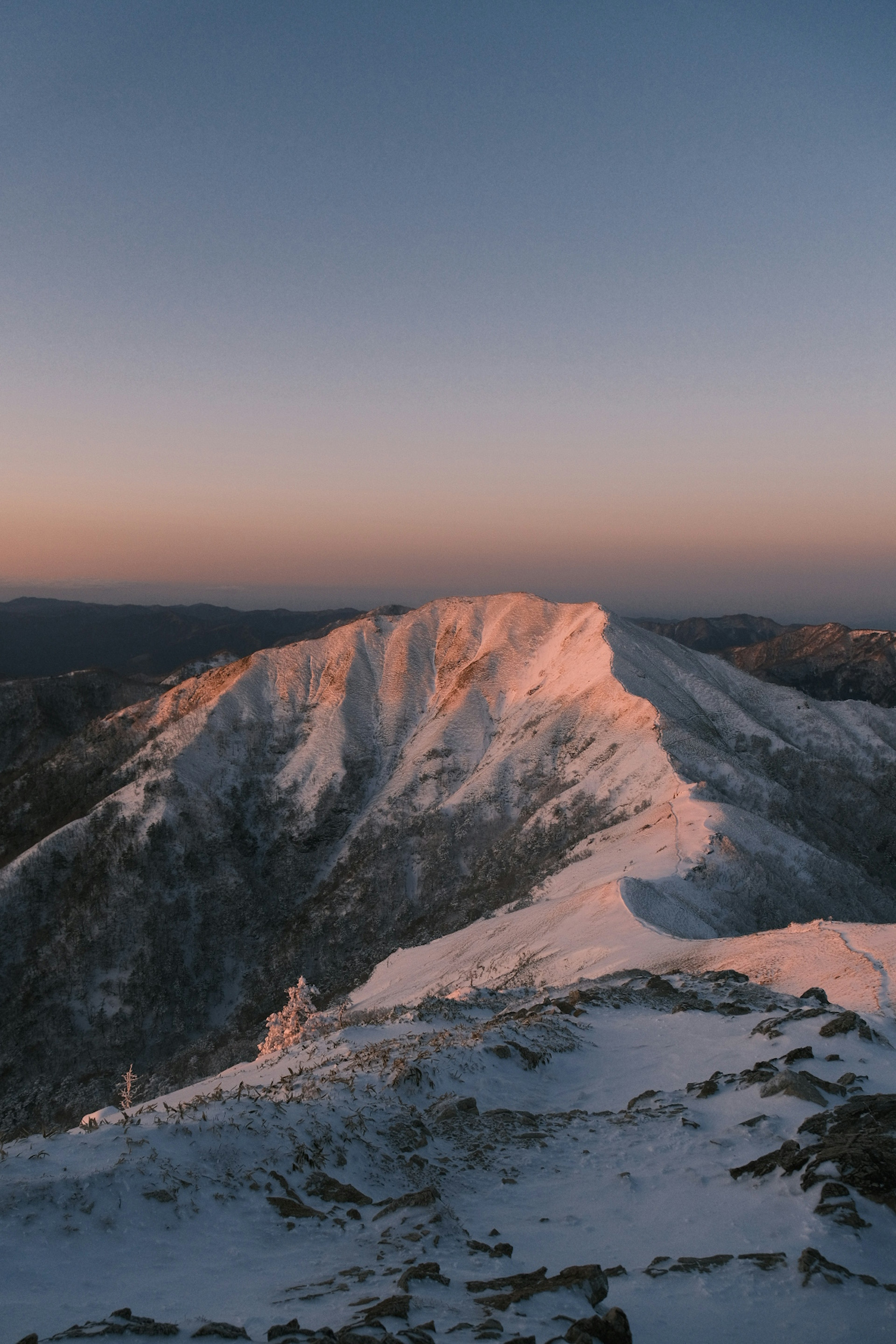 雪に覆われた山の頂上が夕日に照らされている風景