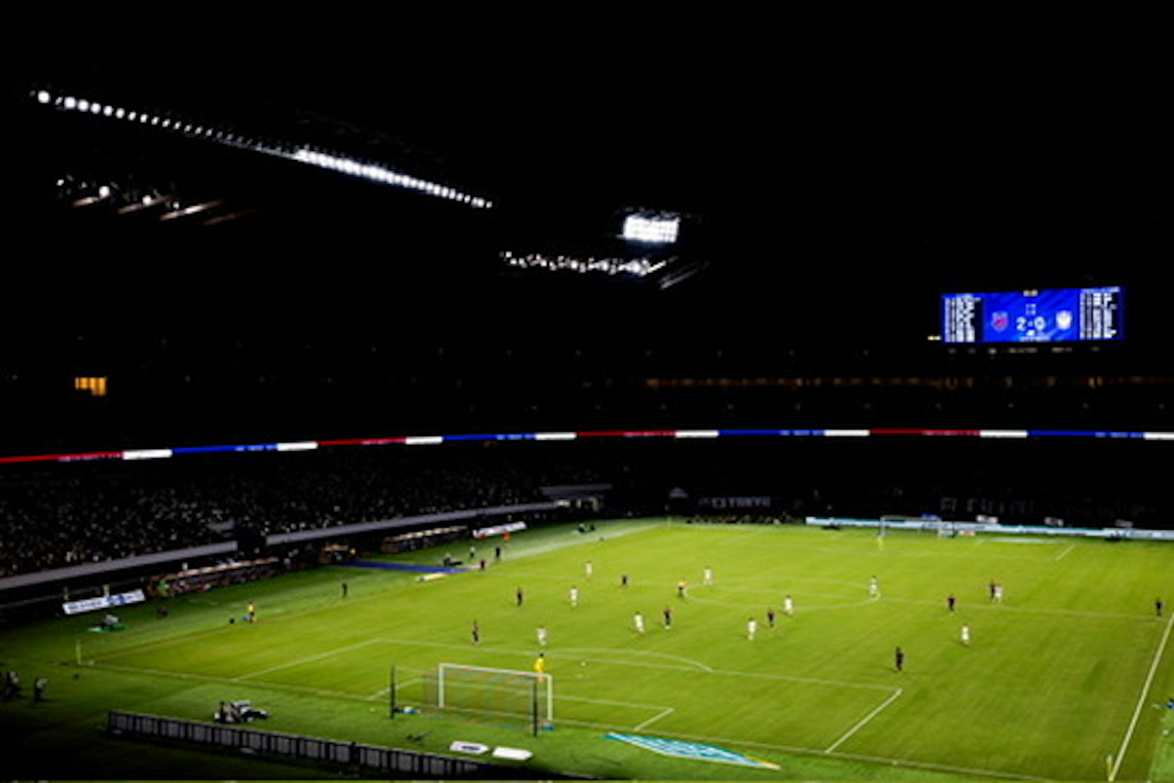 Un partido de fútbol que se lleva a cabo por la noche en un estadio