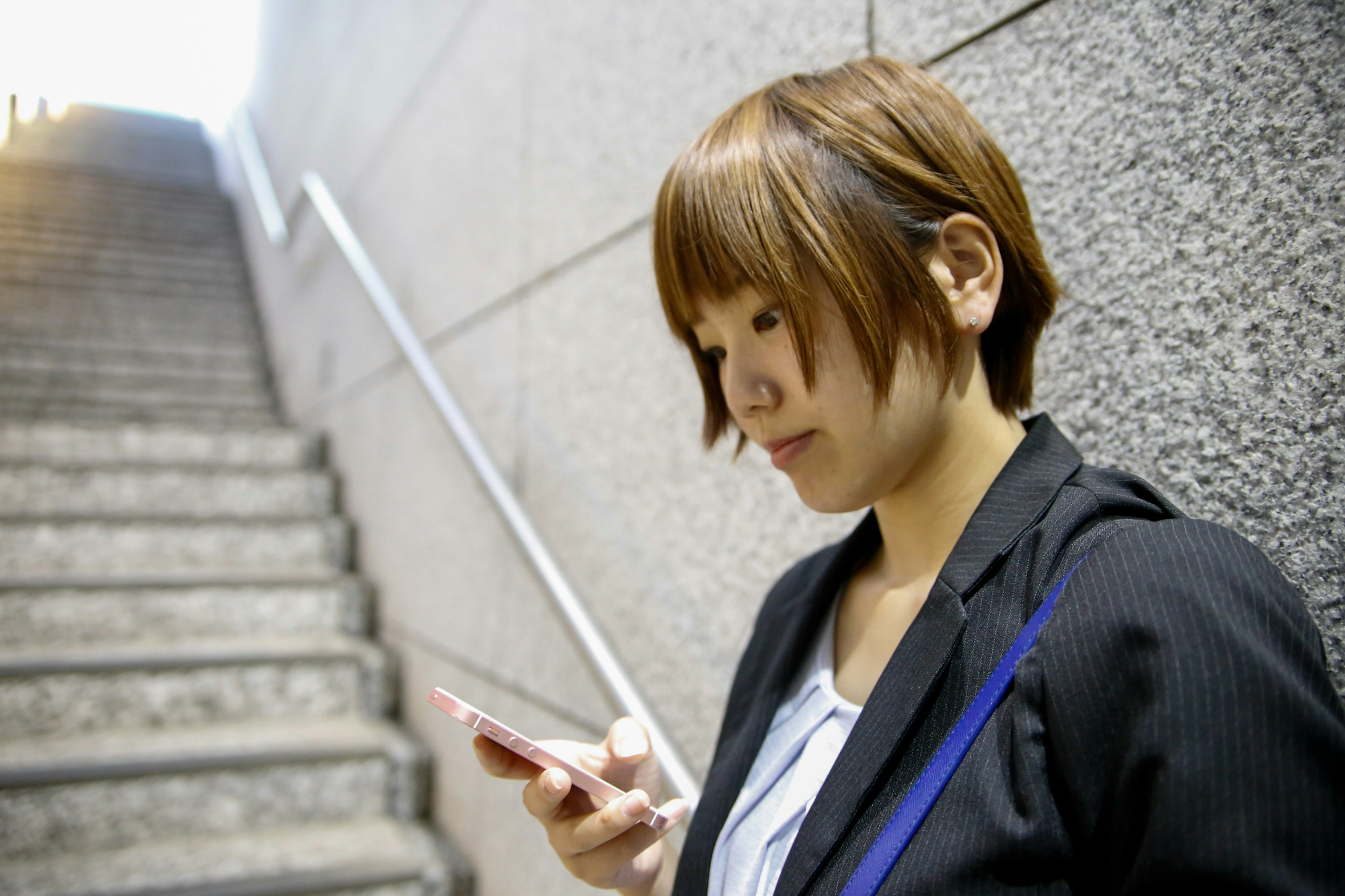 A businesswoman using a smartphone while standing on stairs