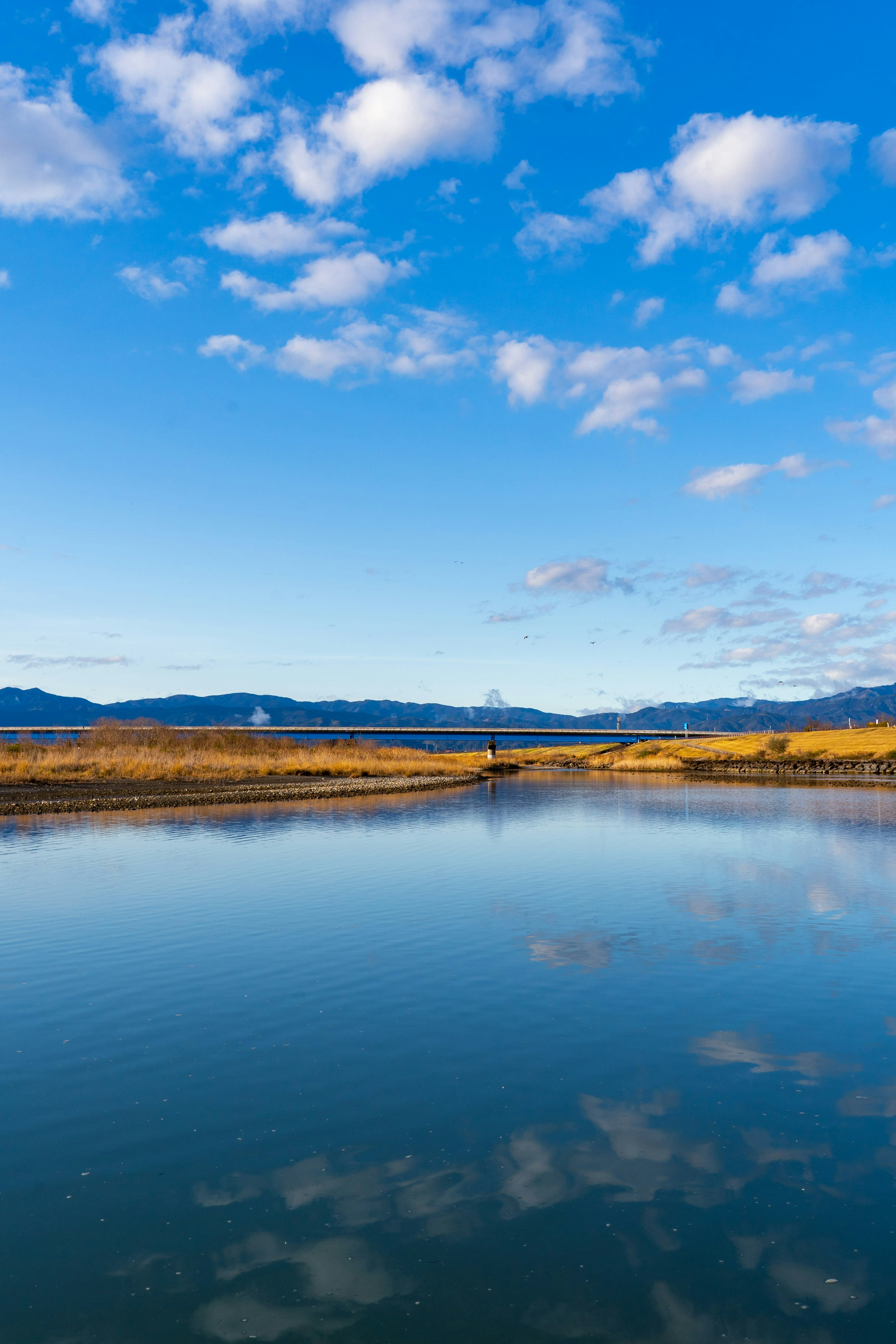 Serene river landscape with blue sky and reflected clouds