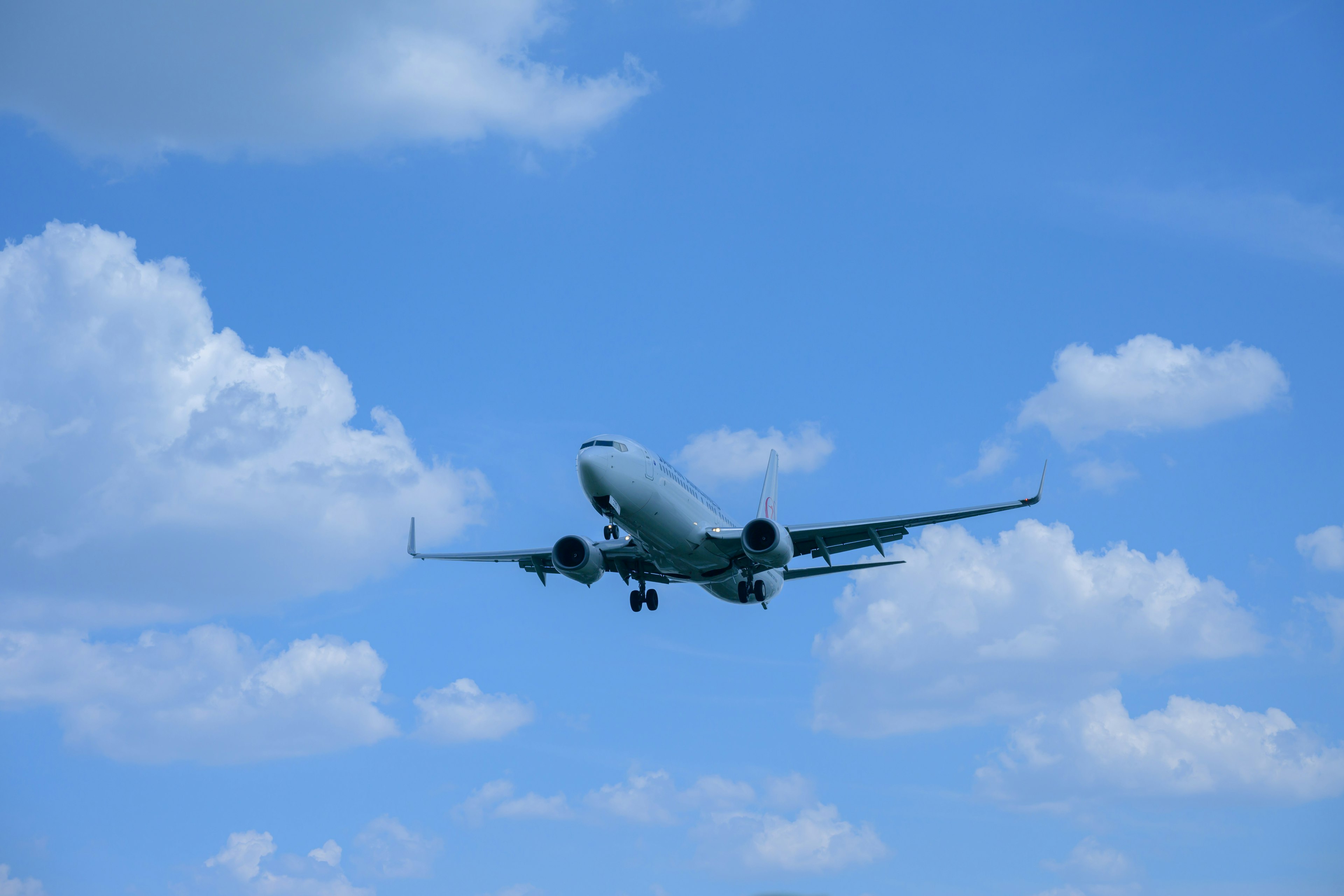 Avión volando en un cielo azul con nubes blancas