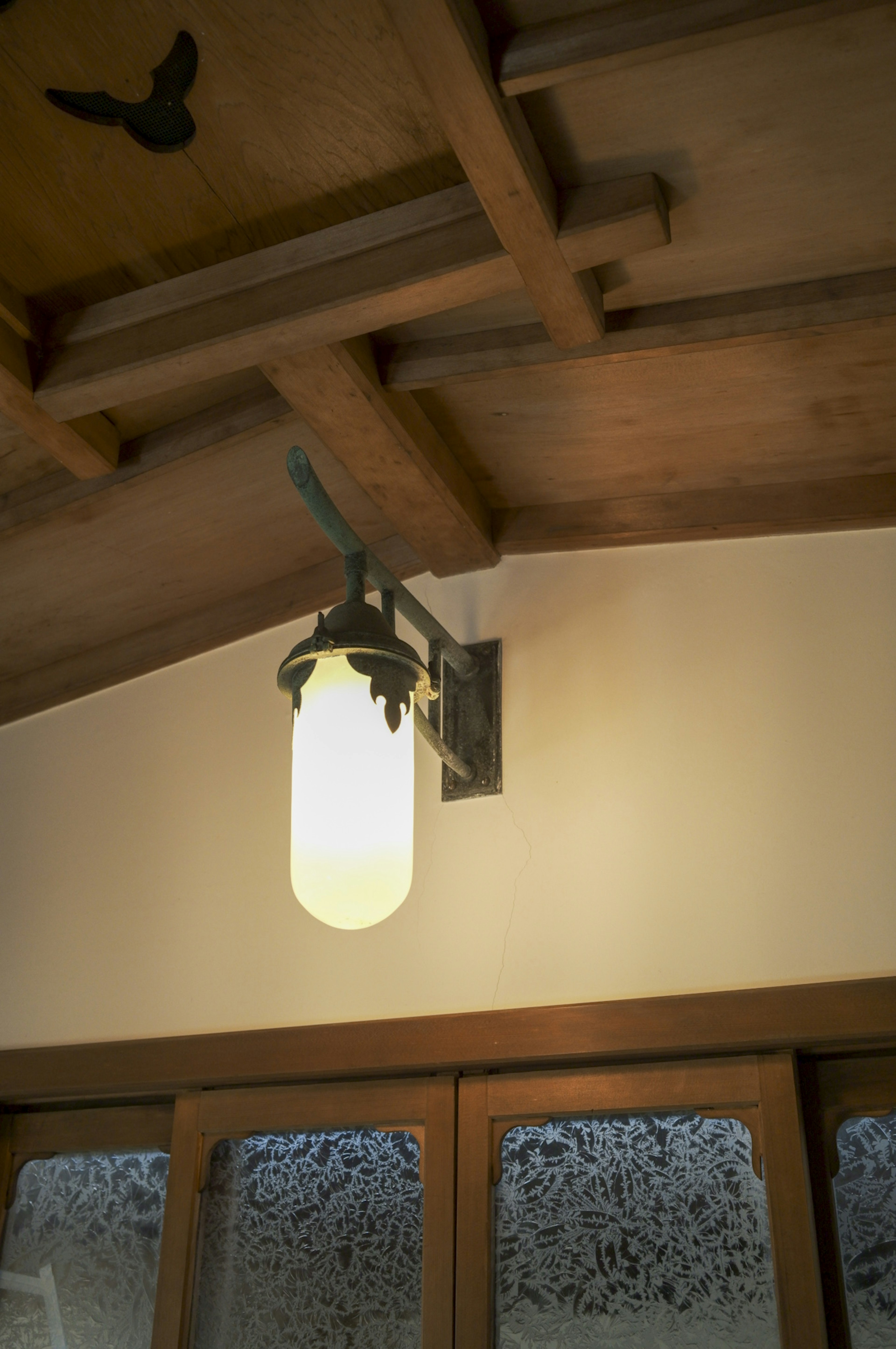 White lamp with black fixture mounted on wooden ceiling