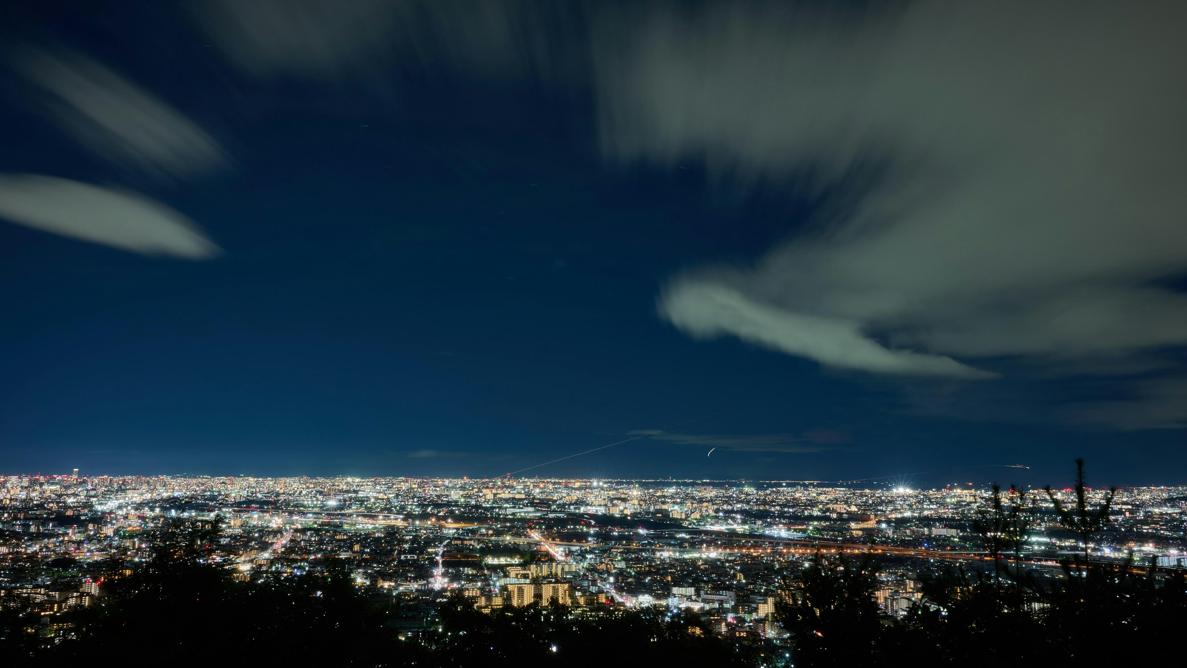 Nachtansicht einer Stadt mit hellen Lichtern und Wolken