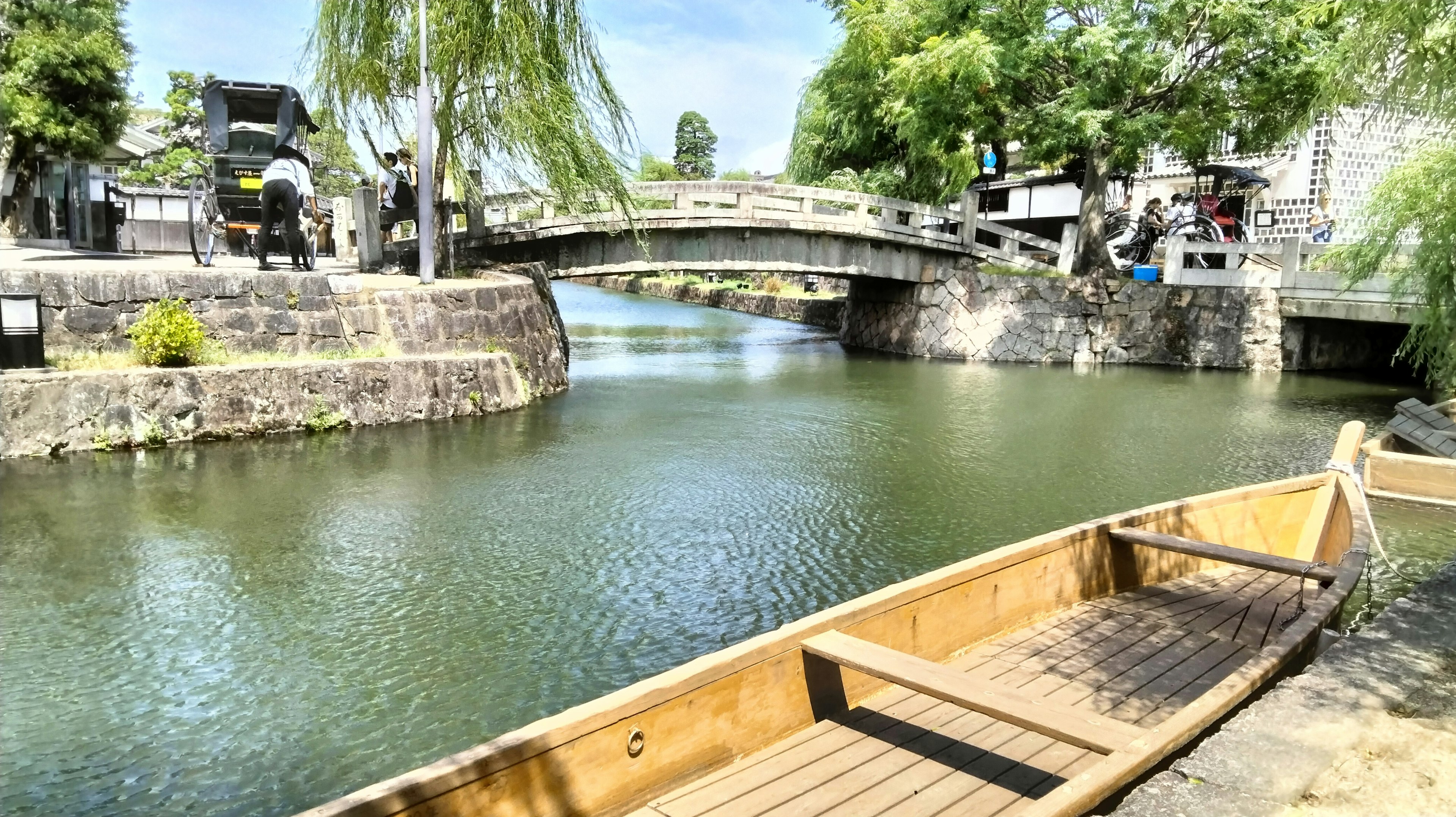 Canal tranquilo con bote de madera puente y árboles verdes a la vista