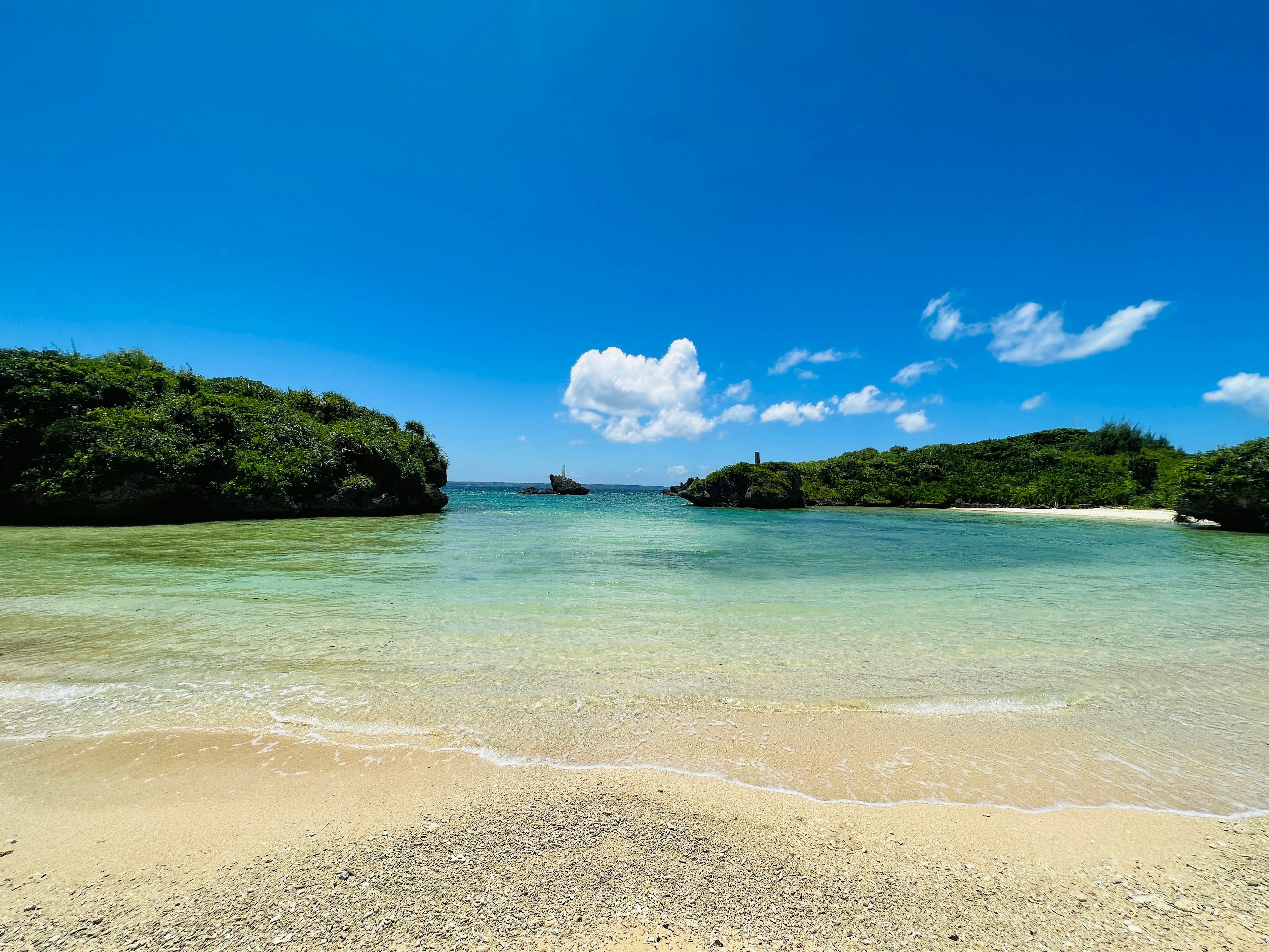 Schöne Strandlandschaft mit blauem Meer grünen Hügeln und weißem Sandstrand