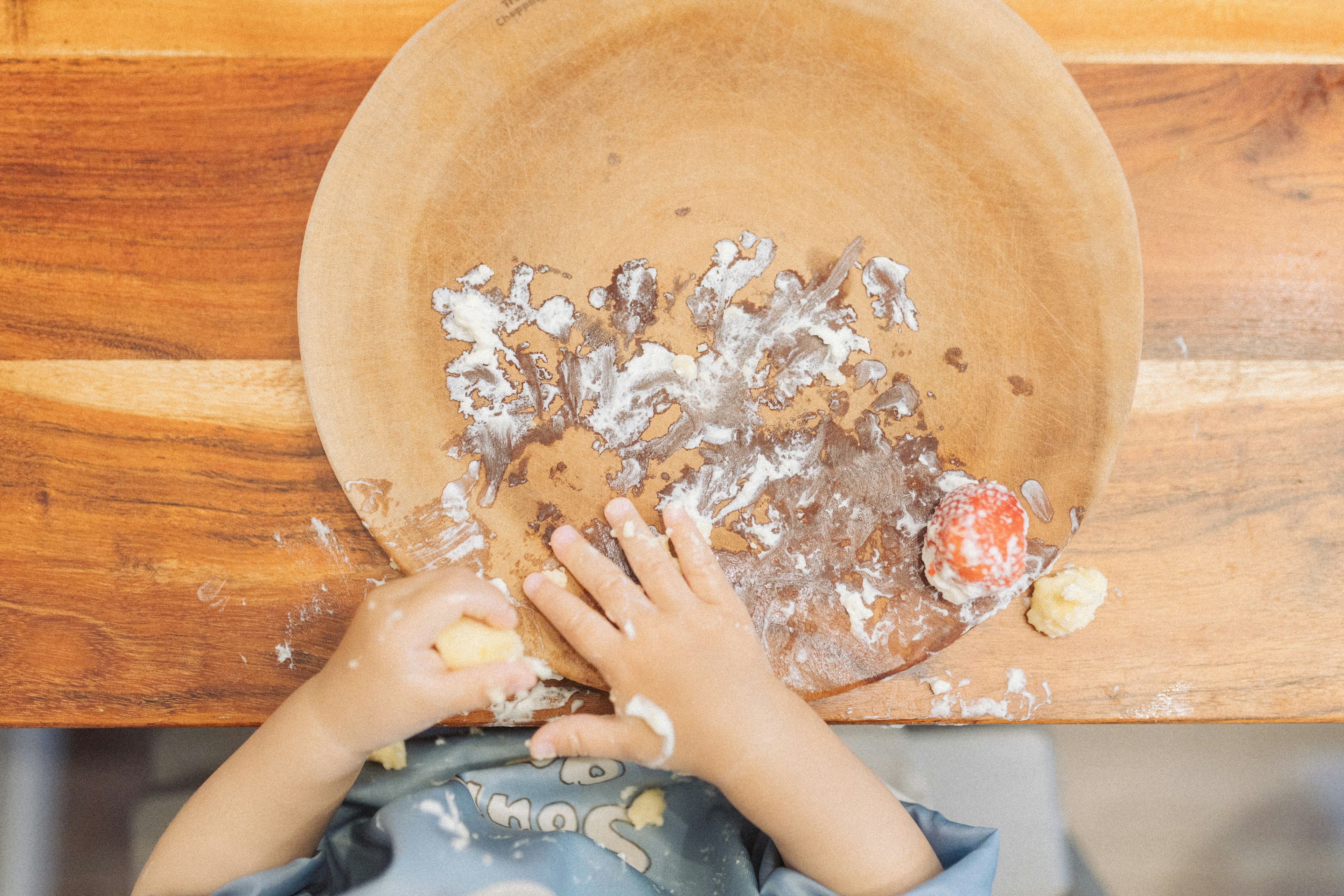 Bambino che gioca con una ciotola di legno con farina e cibo sparsi