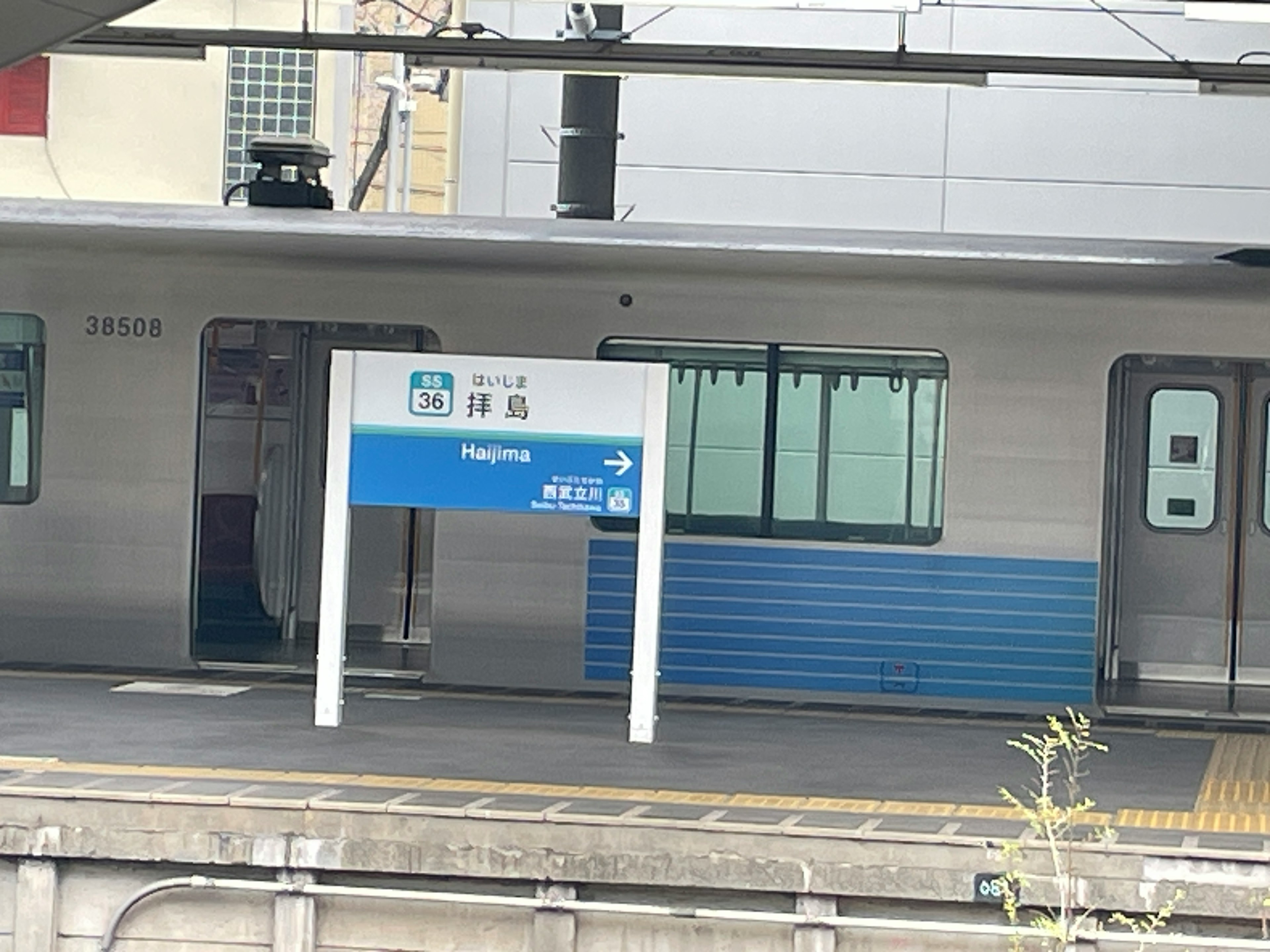 Train station platform with blue sign and white building