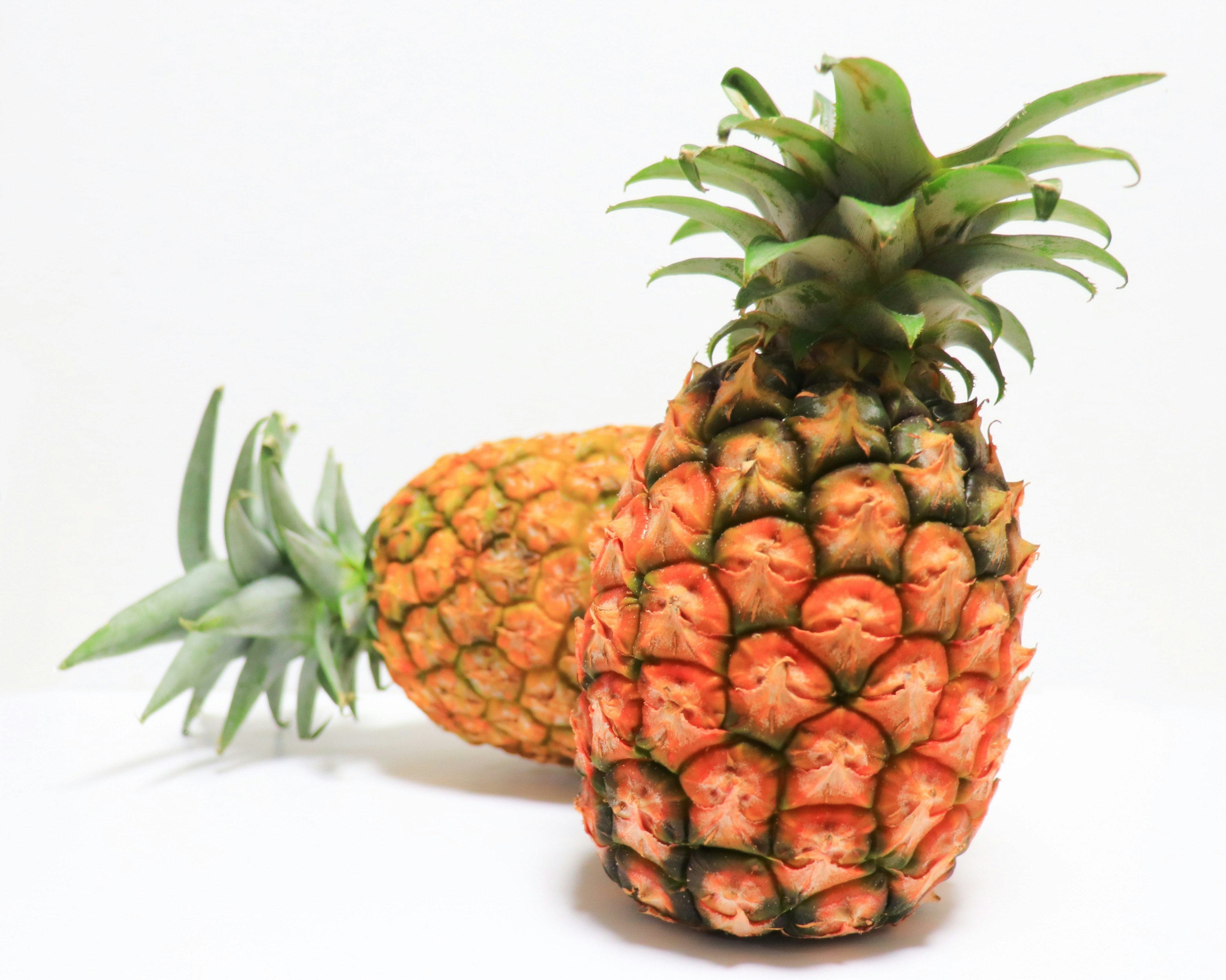 Two pineapples displayed on a white background