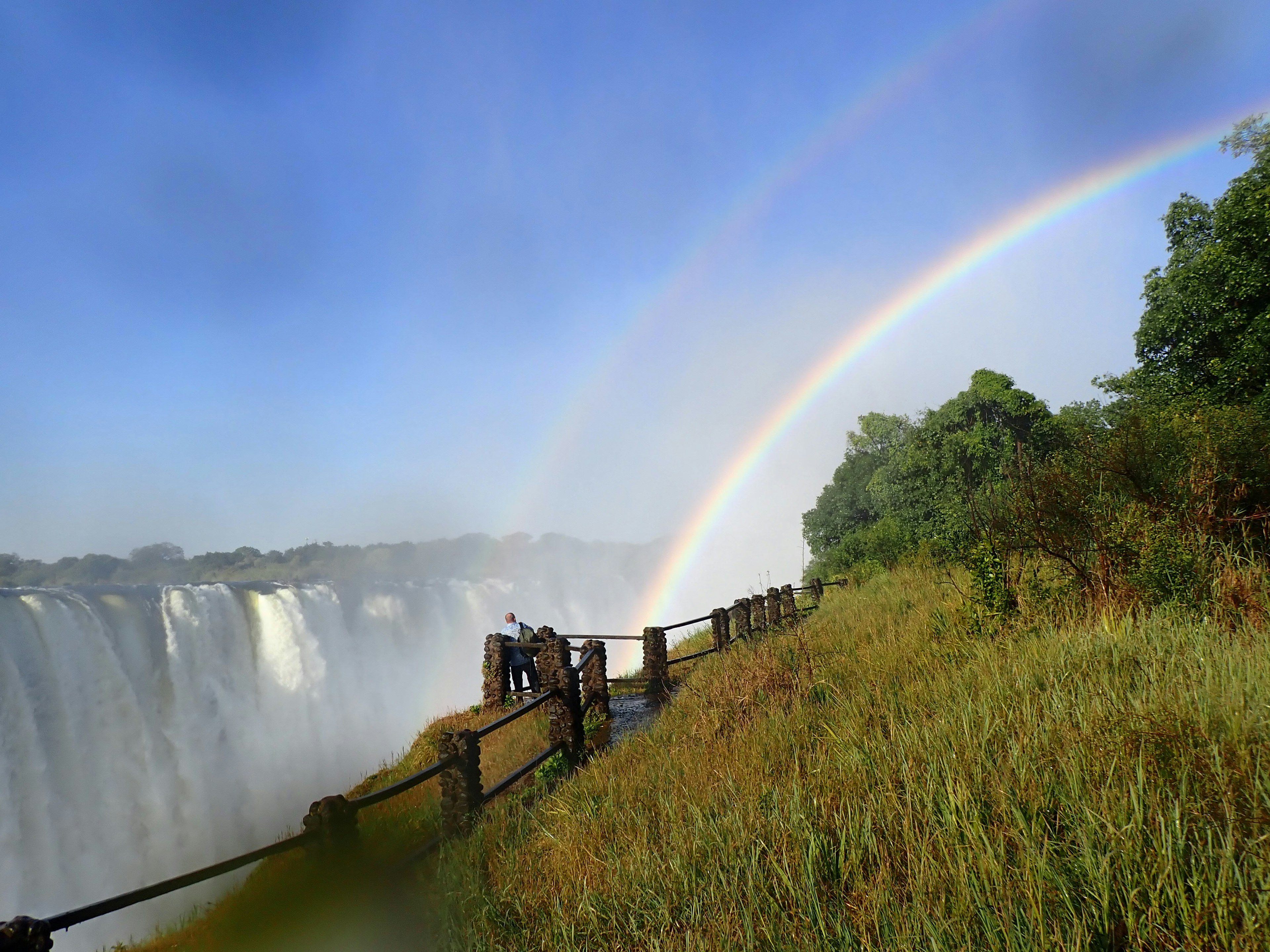 Beeindruckende Aussicht auf die Iguazú-Wasserfälle mit einem doppelten Regenbogen und üppigem Grün