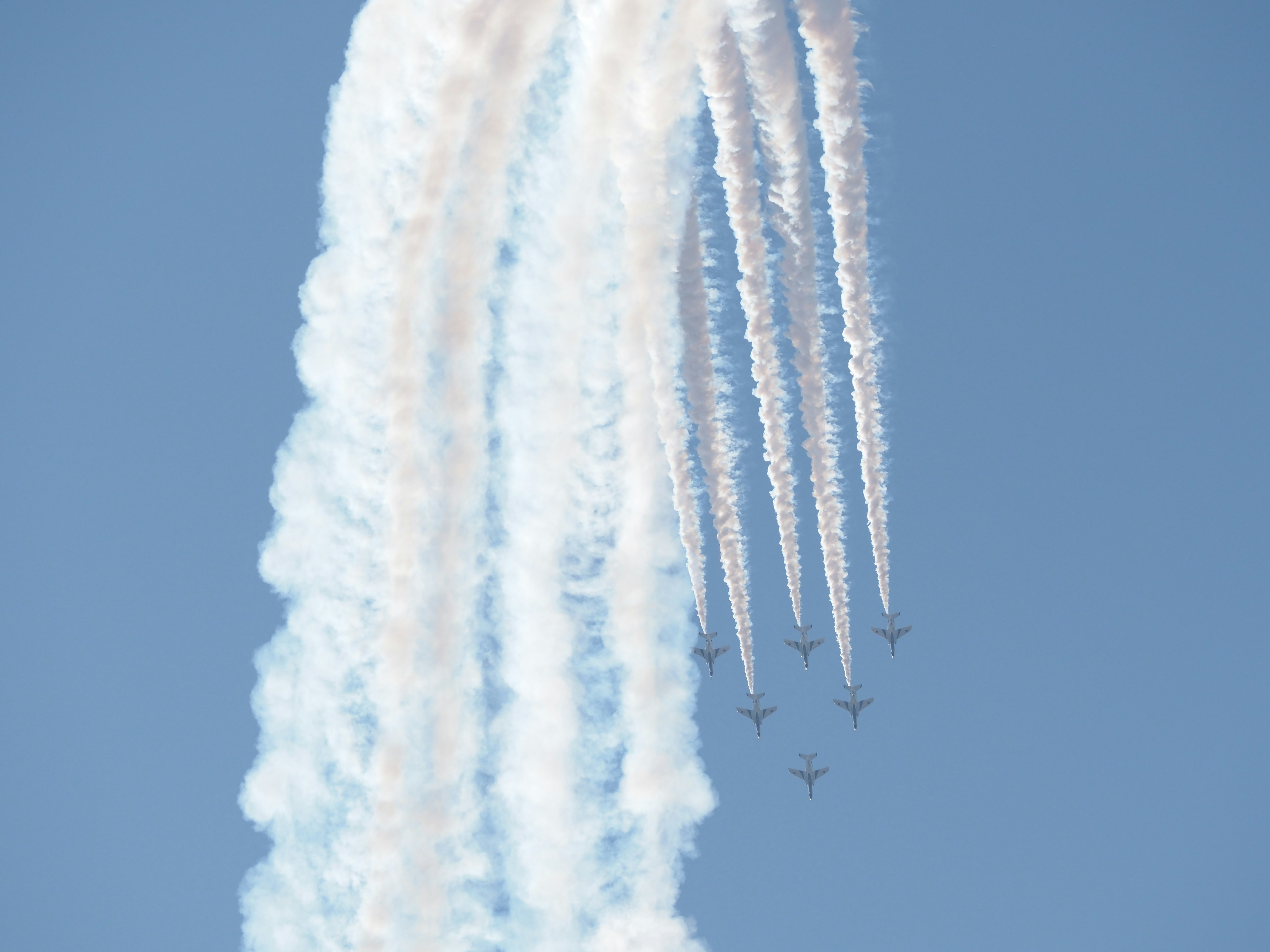 Airplanes creating white smoke trails against a blue sky