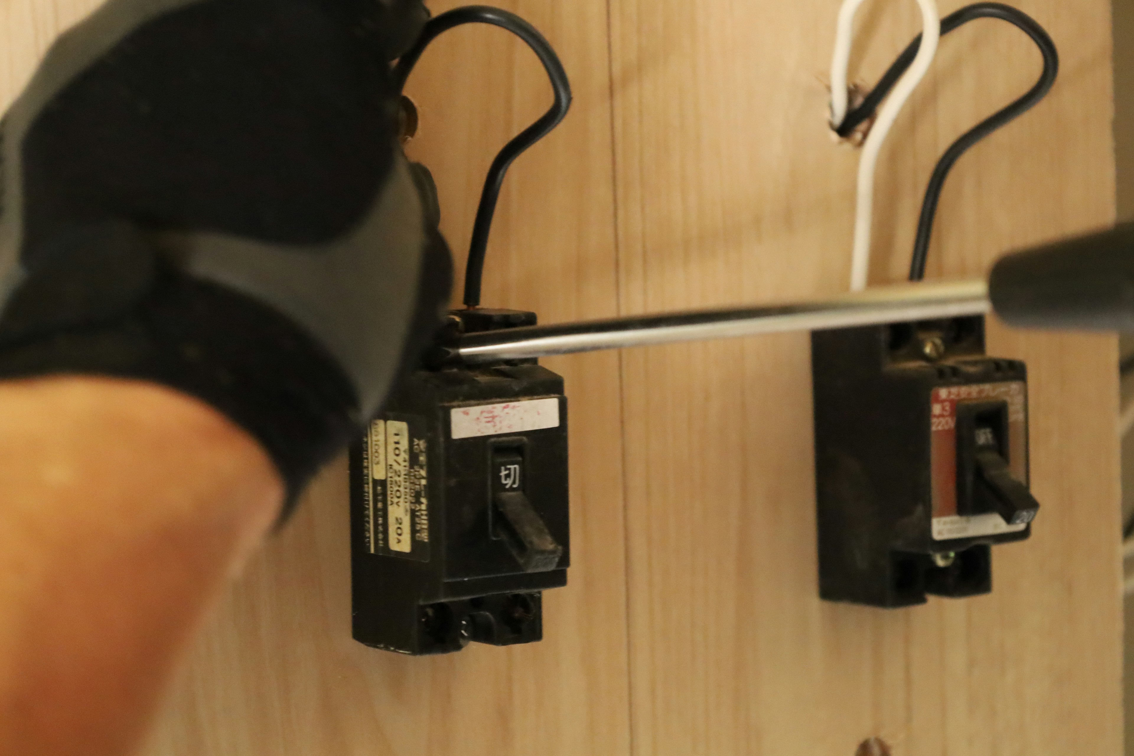 A gloved hand working on electrical circuit breakers