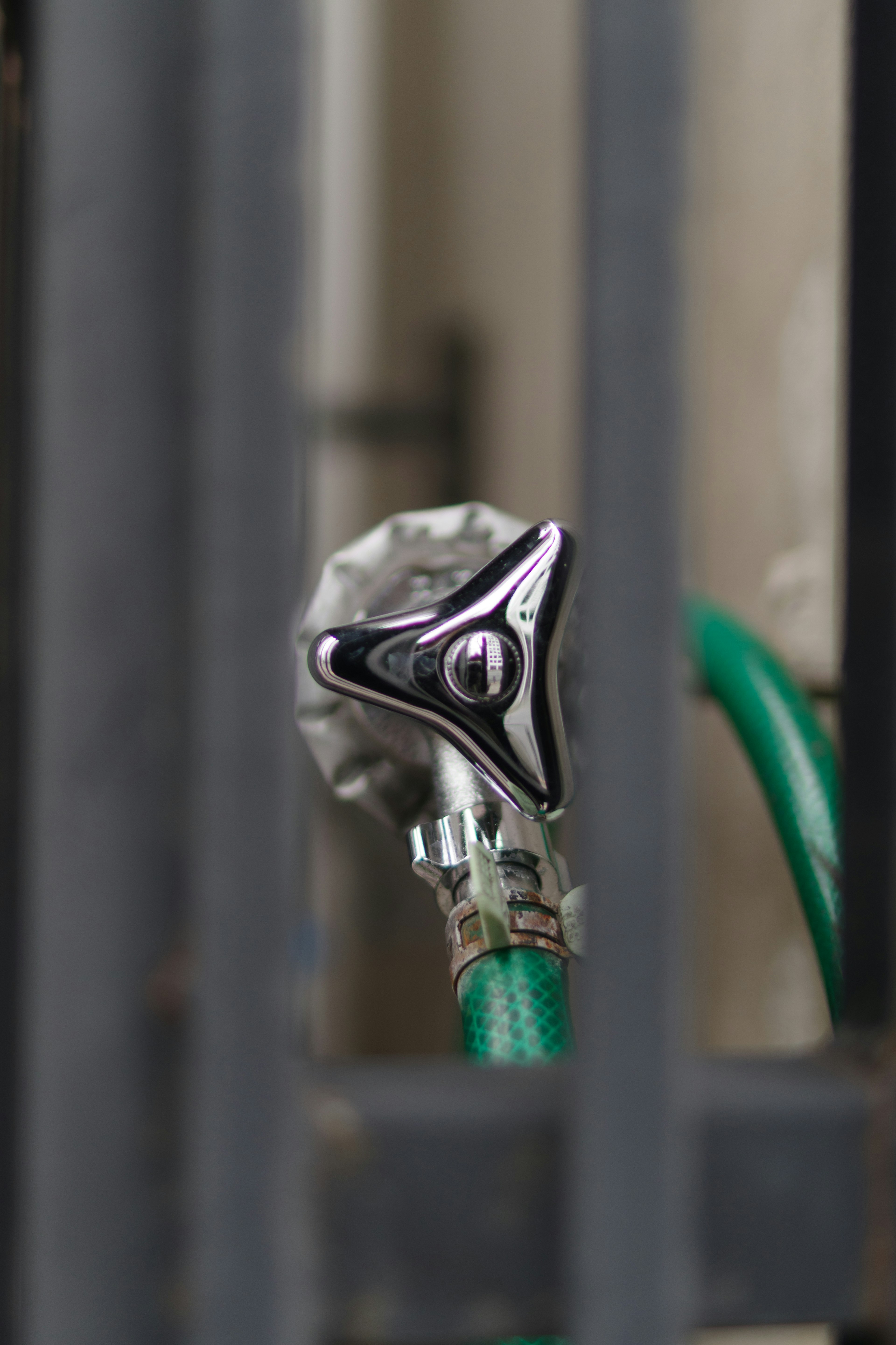 Close-up image of a metal faucet connected to a green hose