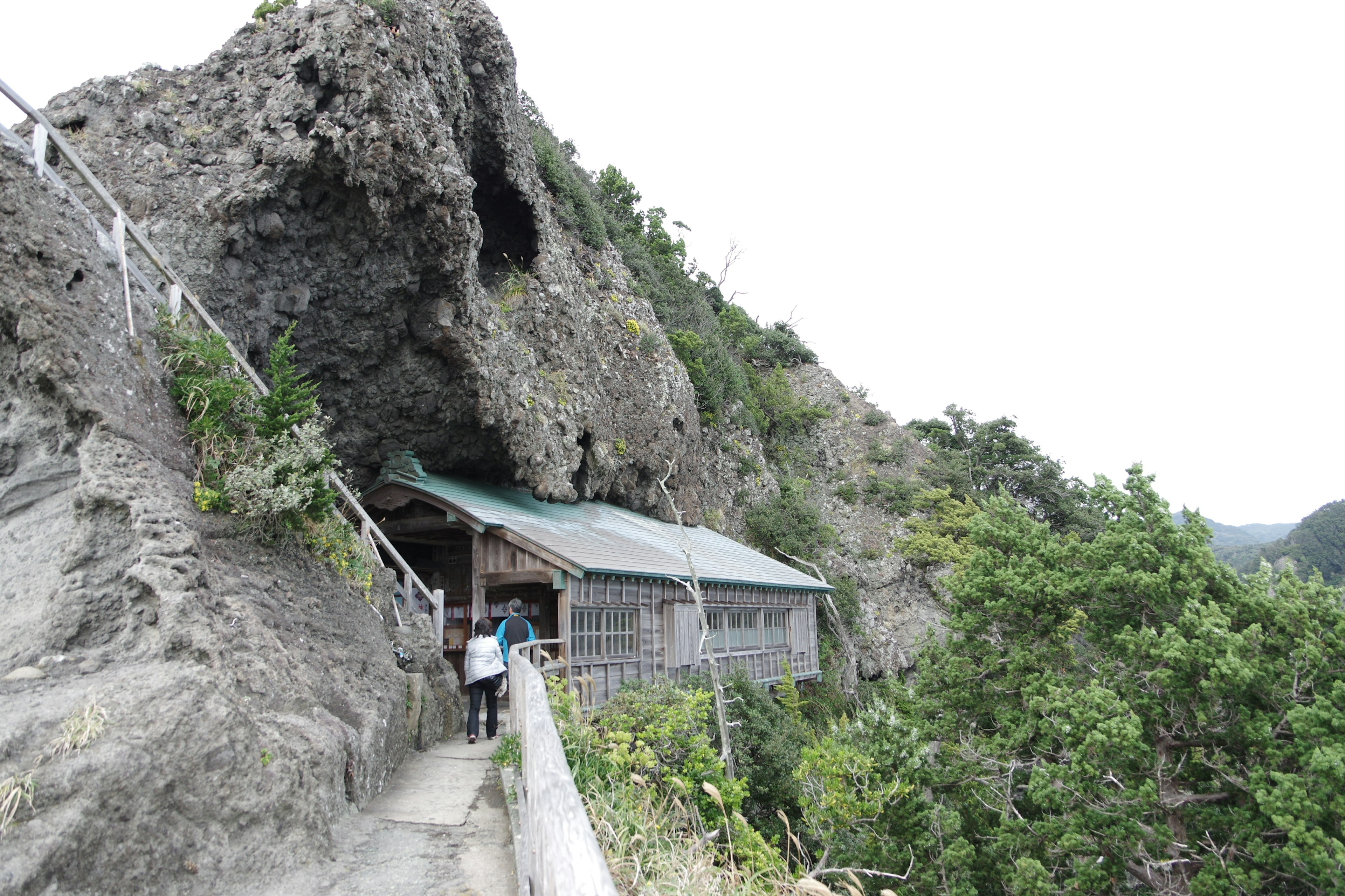 岩の間にある小屋と木の道が見える風景