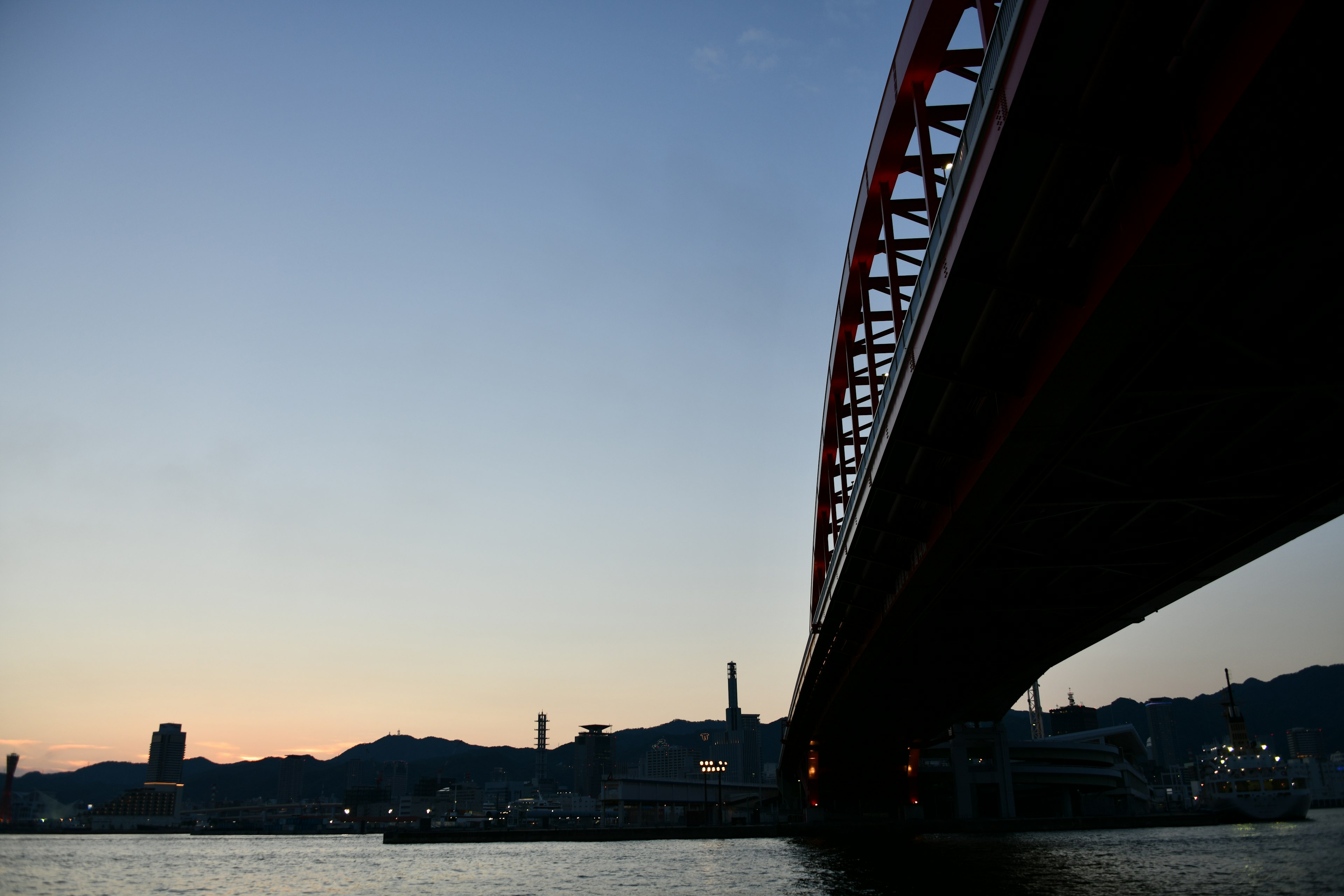 Silhouette of a red bridge at dusk with water reflections