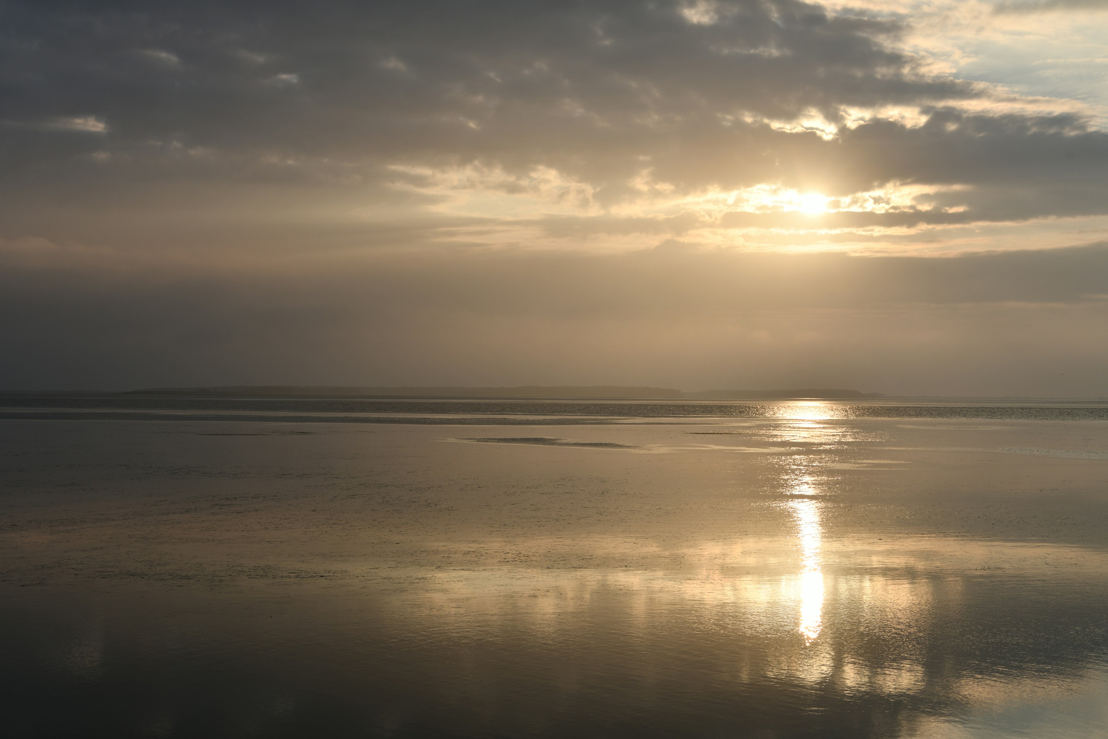 Ruhiger See, der den Sonnenuntergang und die Wolken spiegelt