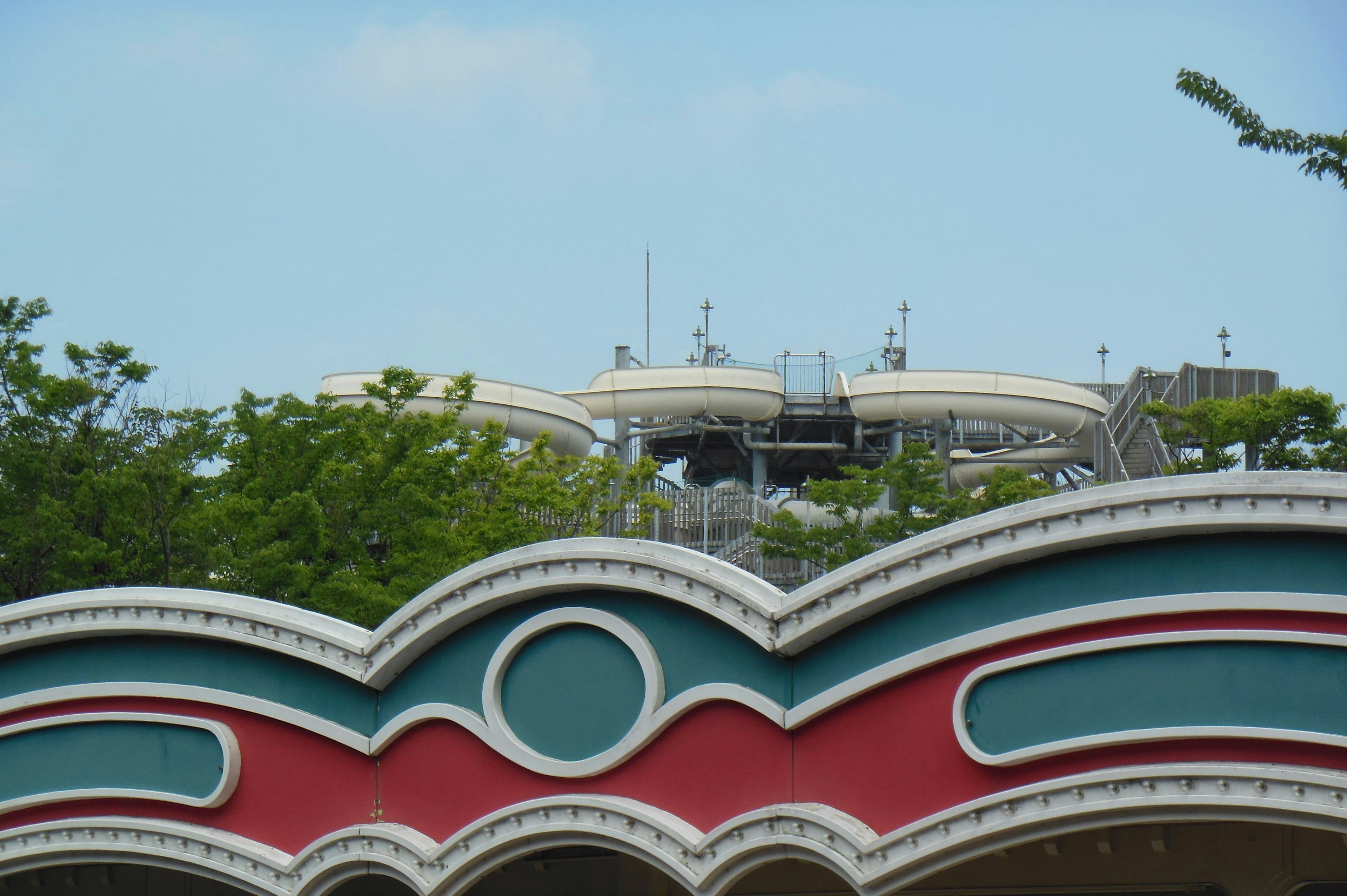 青い空の下にあるカラフルな遊園地の建物とスライダー