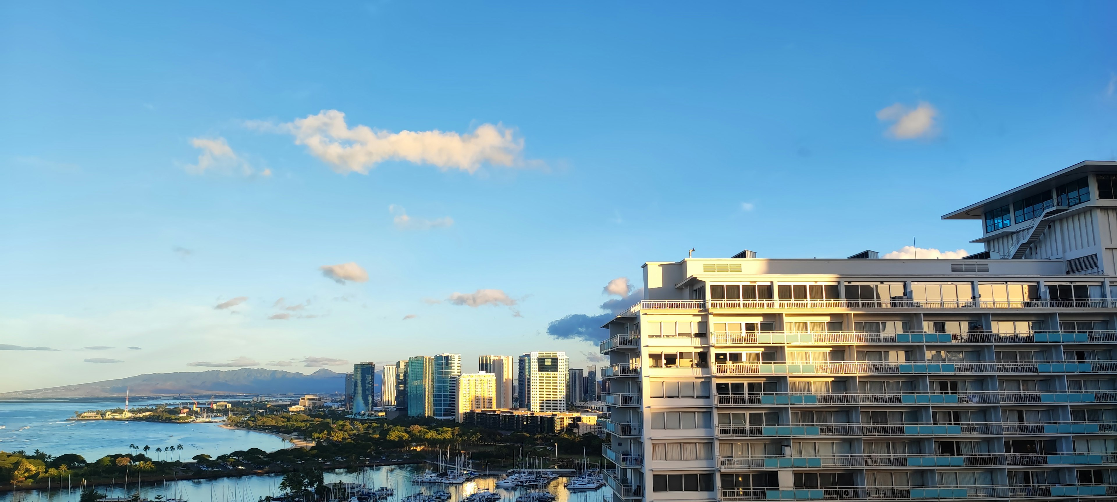 Pemandangan panorama gedung di bawah langit biru dengan awan dan lautan