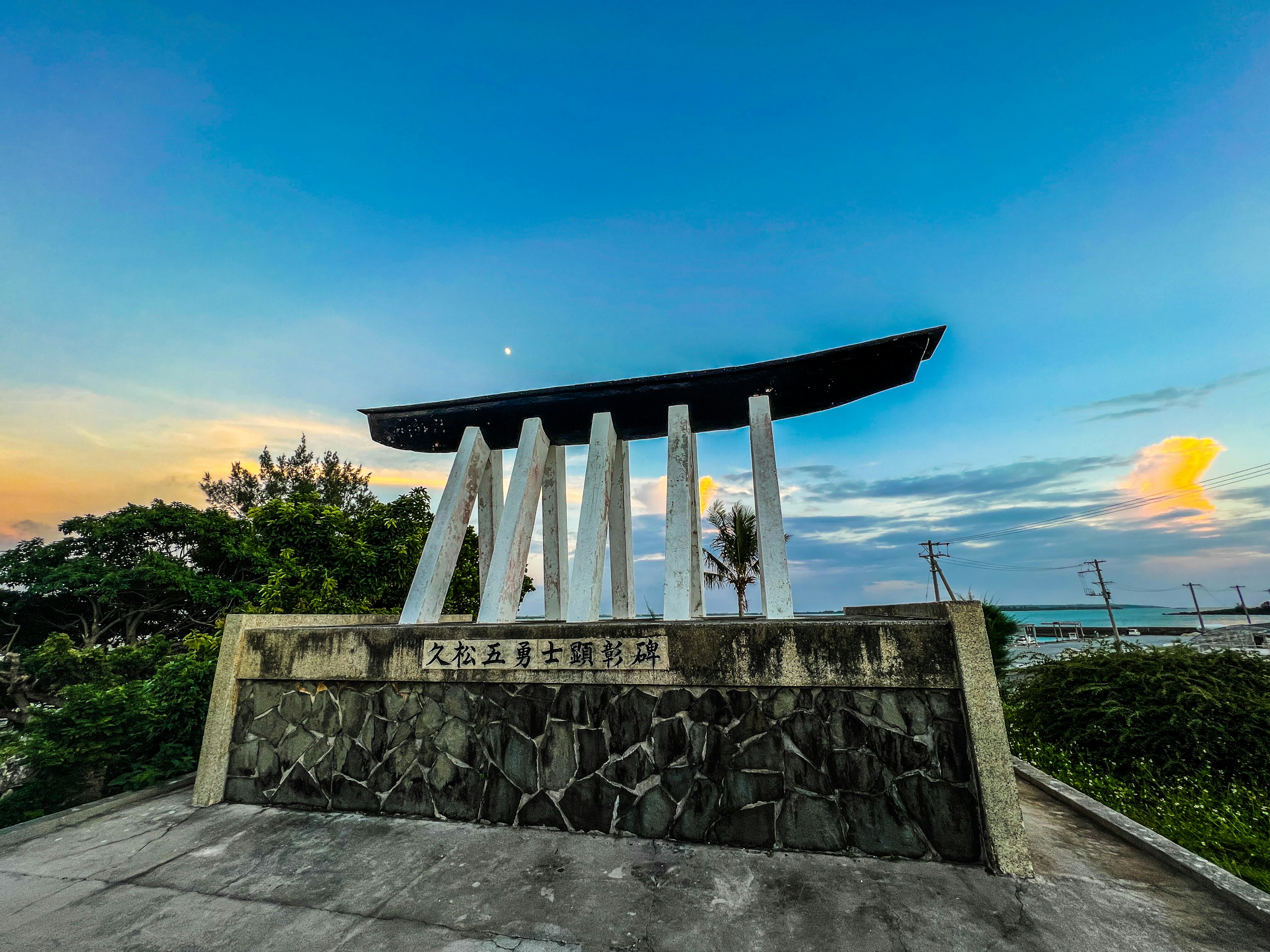 Torii gate structure under a blue sky with orange clouds