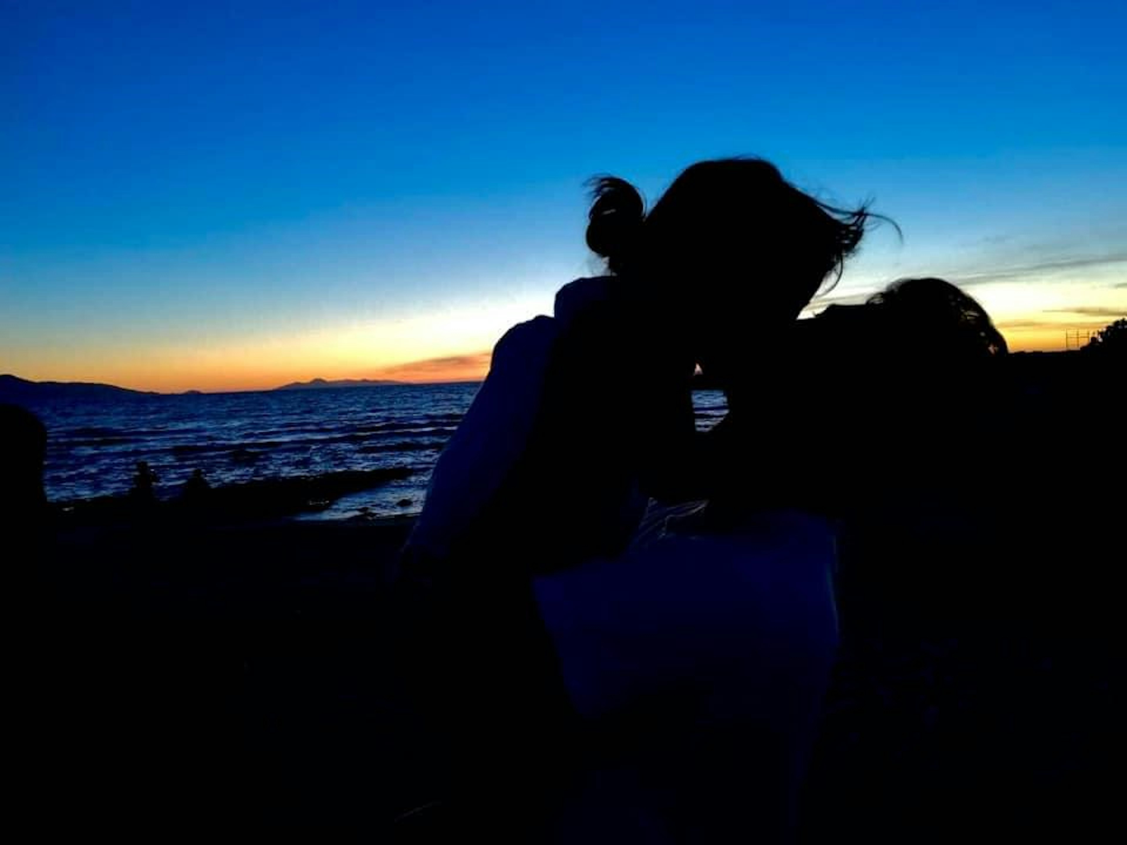 Silhouette of a couple kissing against a sunset