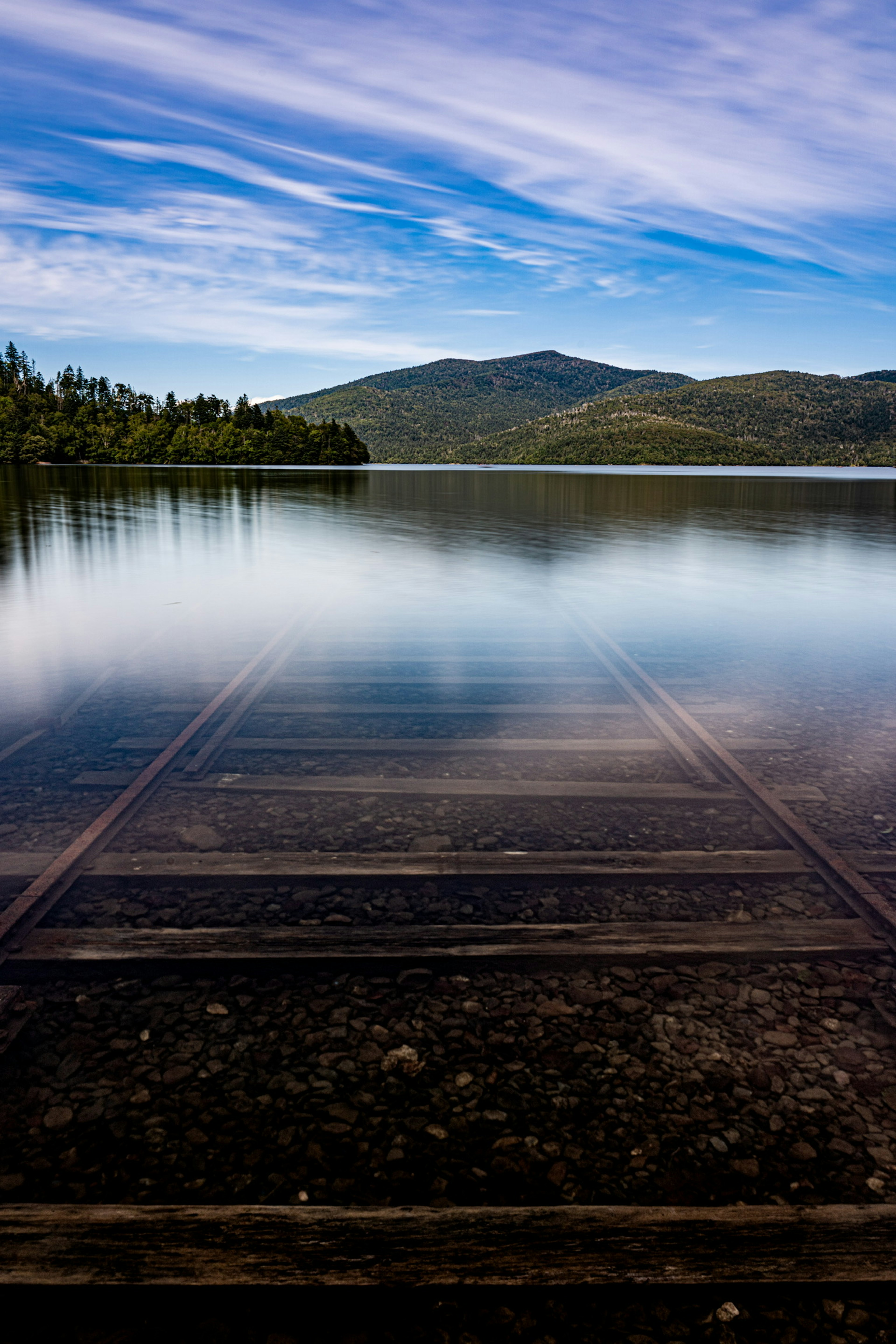 Surface de lac sereine reflétant un beau ciel et des montagnes