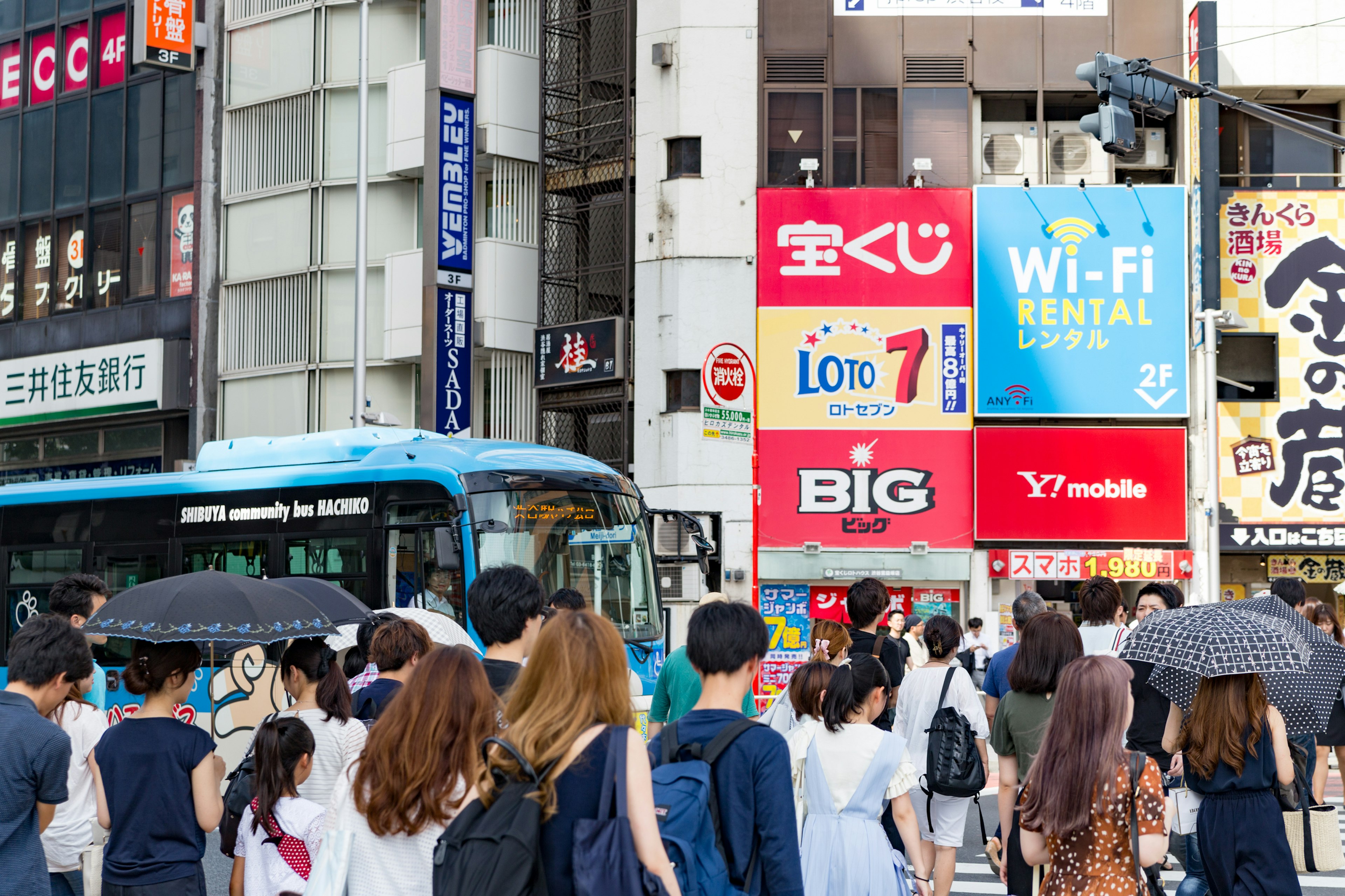 人々が交差点を渡る様子と青いバスのある都市の風景