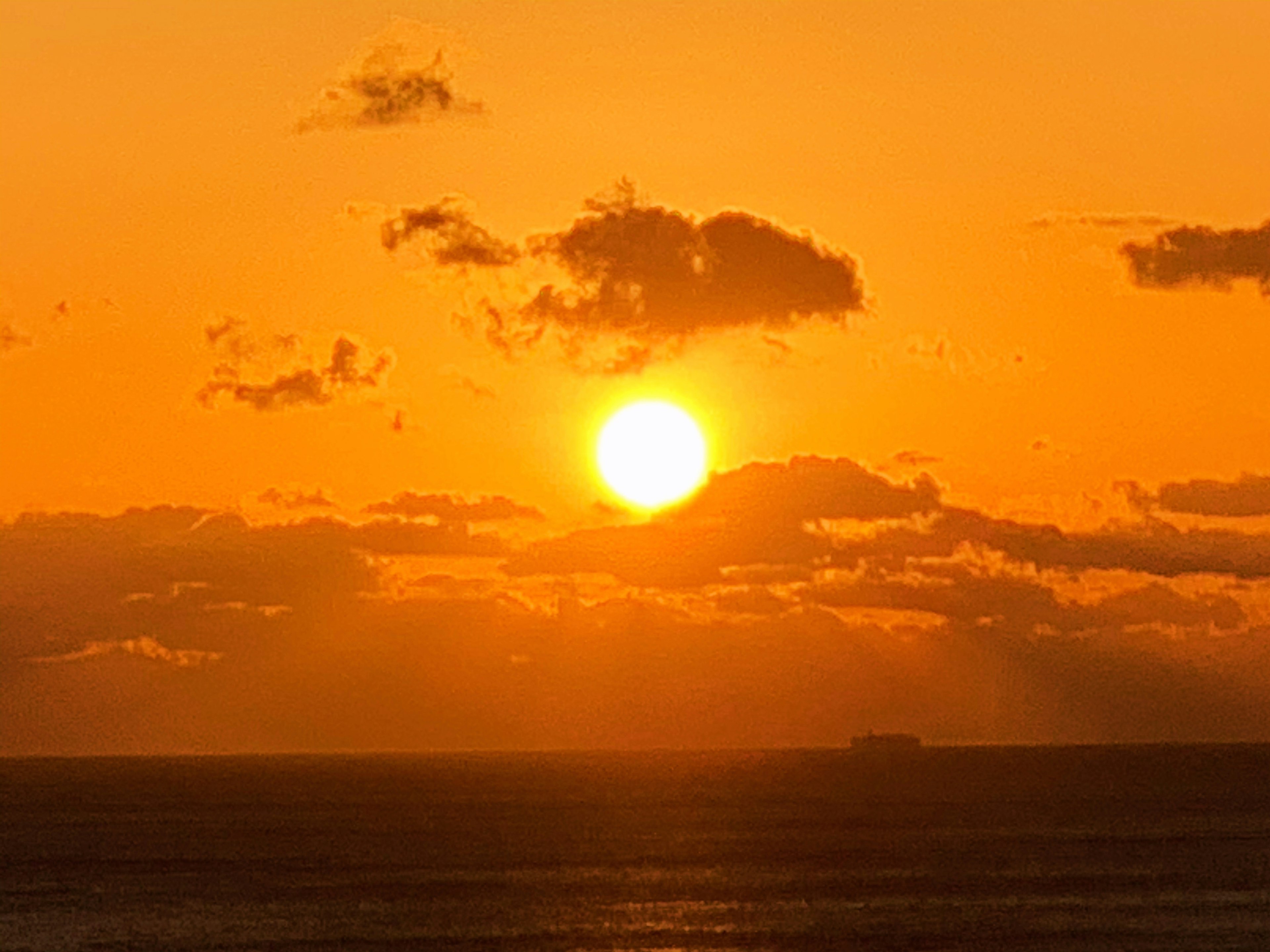 オレンジ色の空に沈む太陽と雲のシルエット