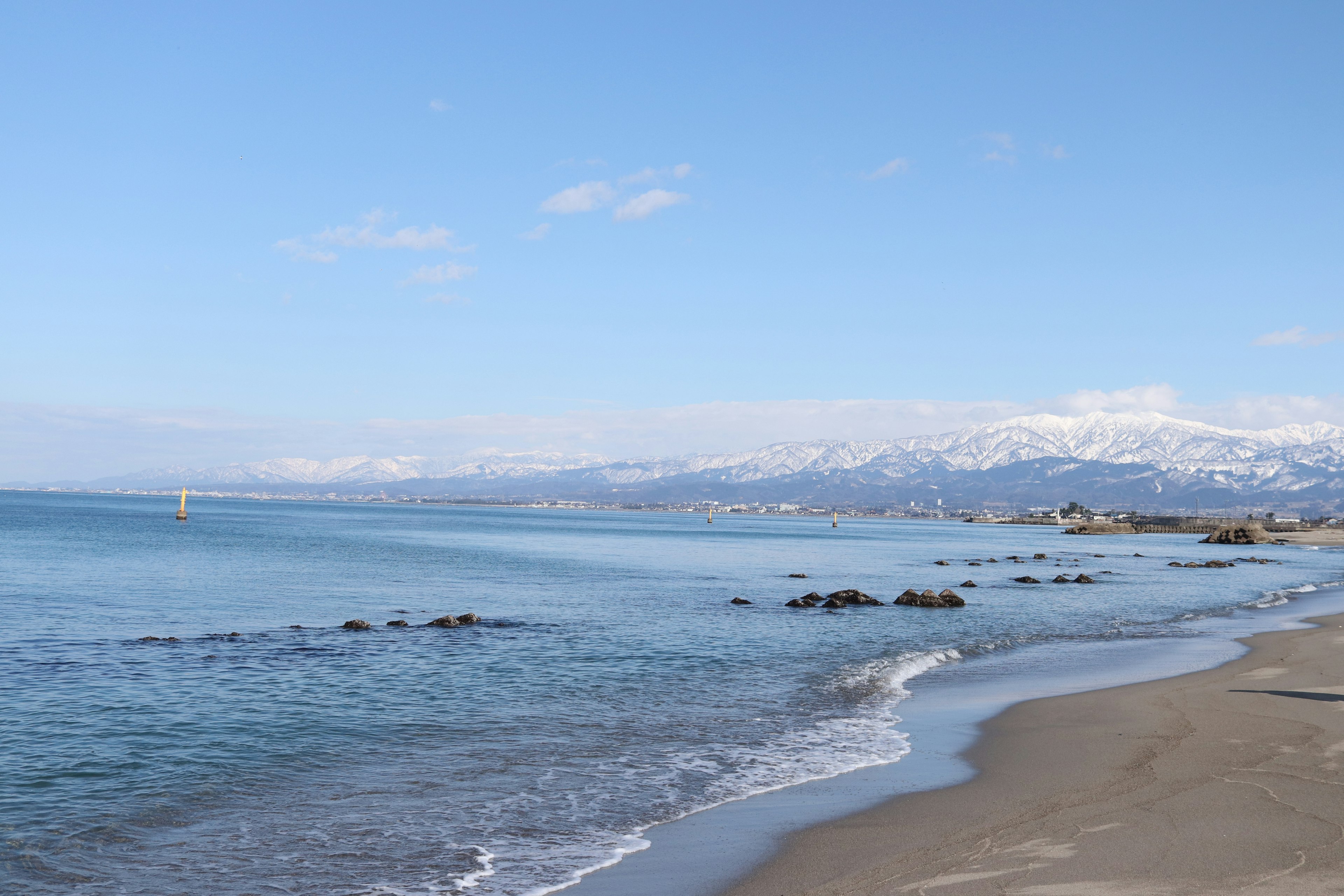 Scenic beach with blue ocean and snow-capped mountains