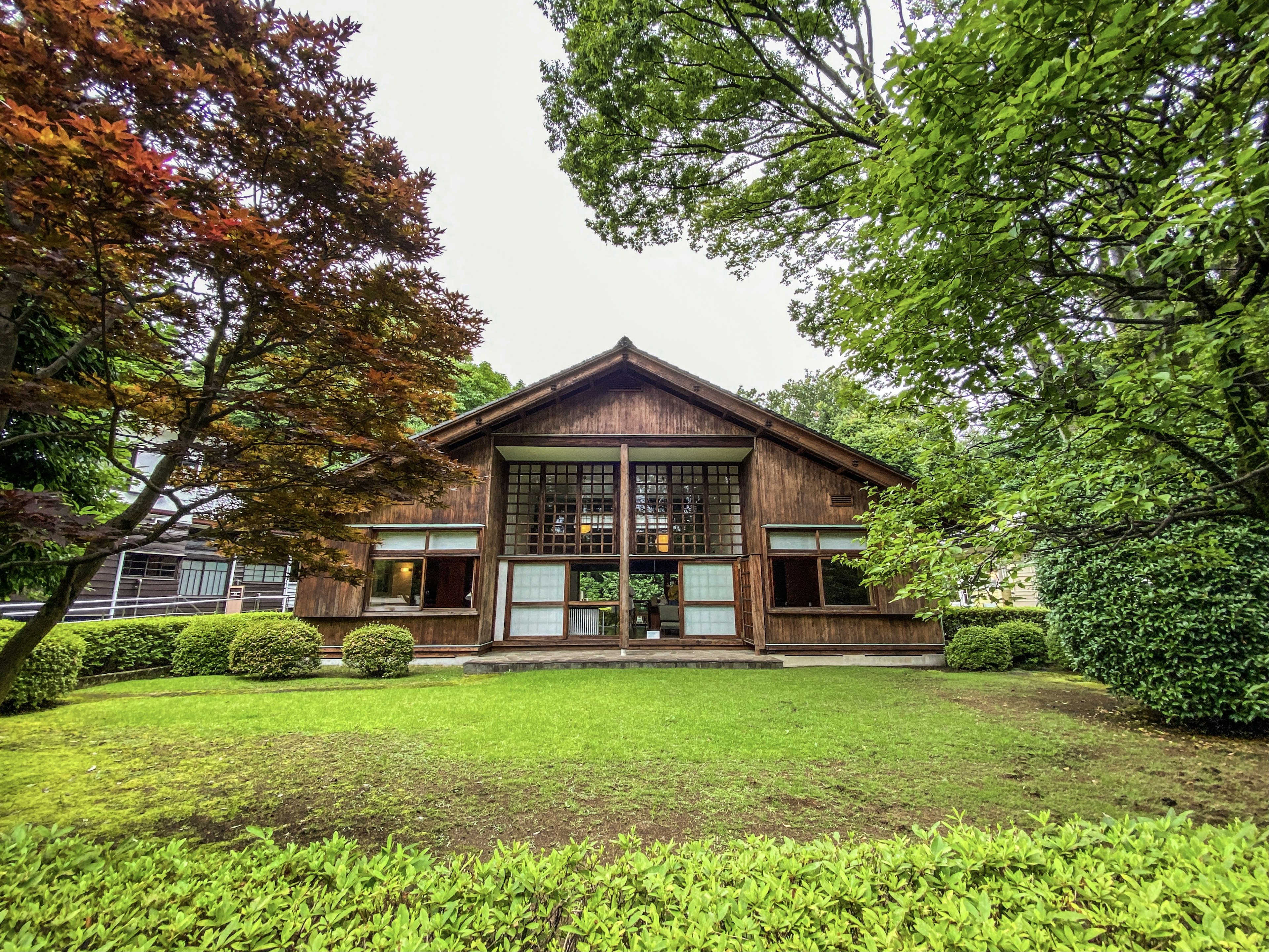 Extérieur d'une maison en bois entourée d'un jardin luxuriant avec des arbres verts et une pelouse bien entretenue