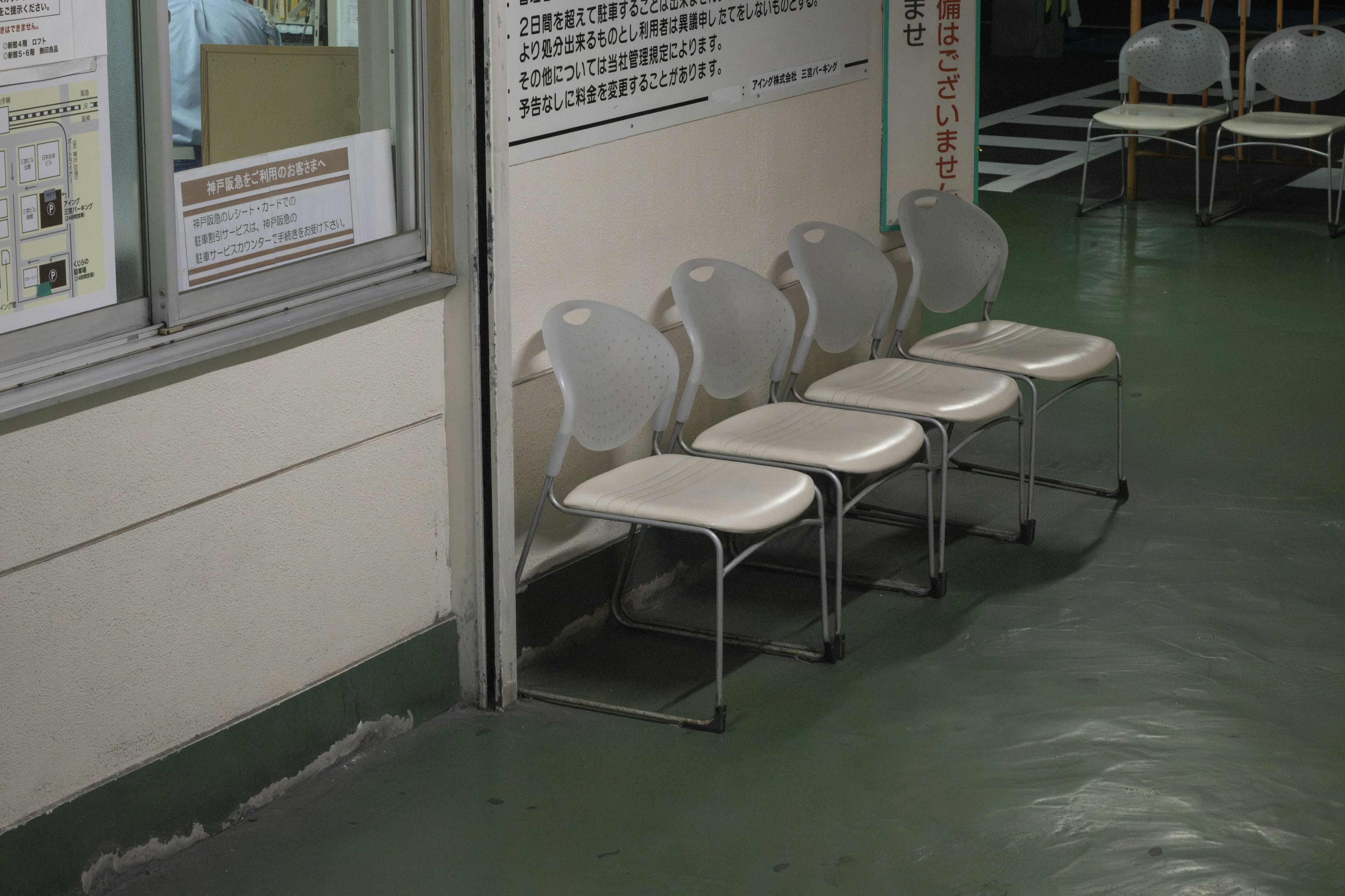 A corner of a waiting room with white chairs arranged